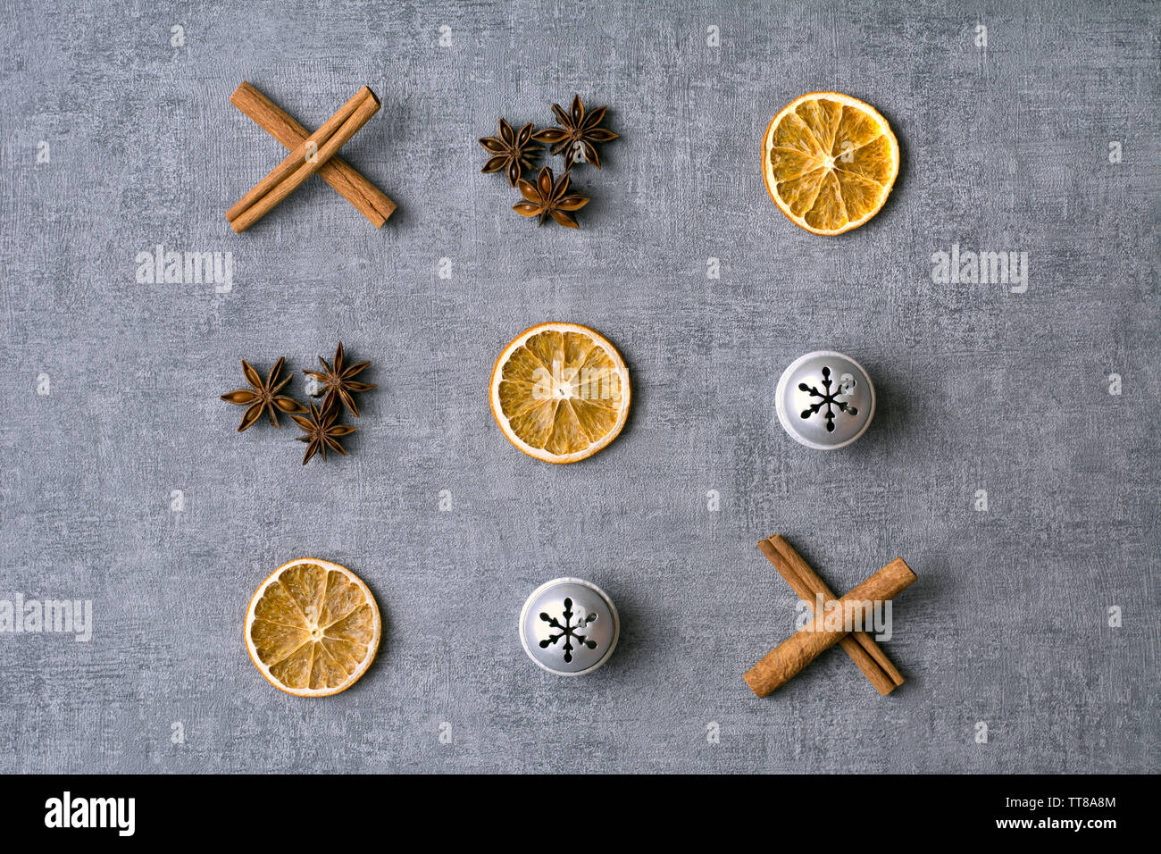 Déco de Noël et des zéros traverse avec des oranges séchées, bâtons de cannelle, anis et Silver Bells sur fond gris Banque D'Images