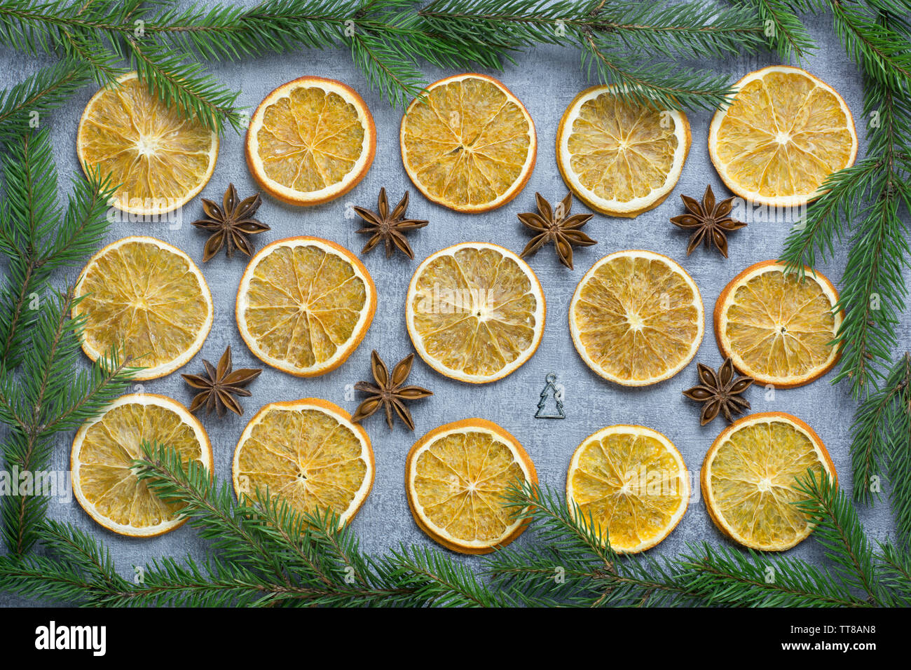 Décoration de Noël avec même des rangées de bagues d'orange séchée, d'anis étoile et un petit arbre de Noël d'argent sur fond gris avec des branches de sapins bo Banque D'Images