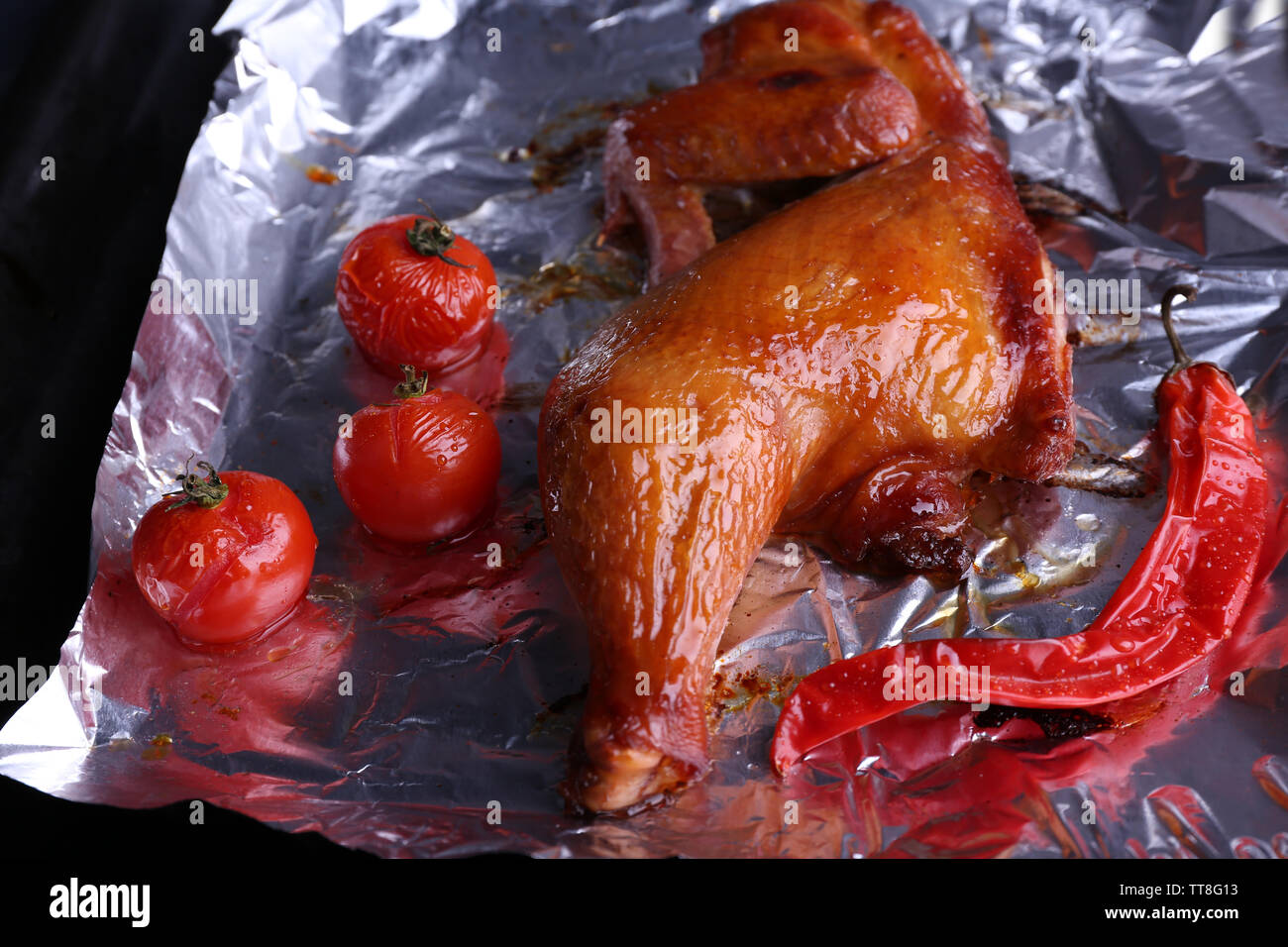 Cuisse de poulet fumé avec des tomates cerises sur l'aluminium close up Banque D'Images