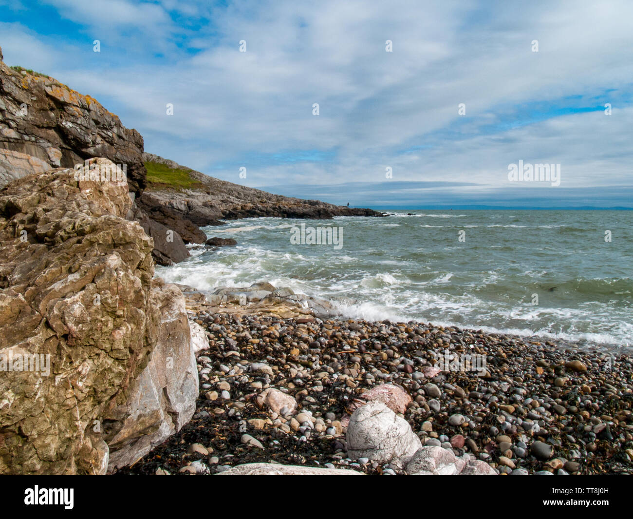 Face à la mer à Limeslade Bay, un pêcheur peut être vu la pêche sur les rochers au loin. Gower, Swansea, Pays de Galles, Royaume-Uni. Banque D'Images