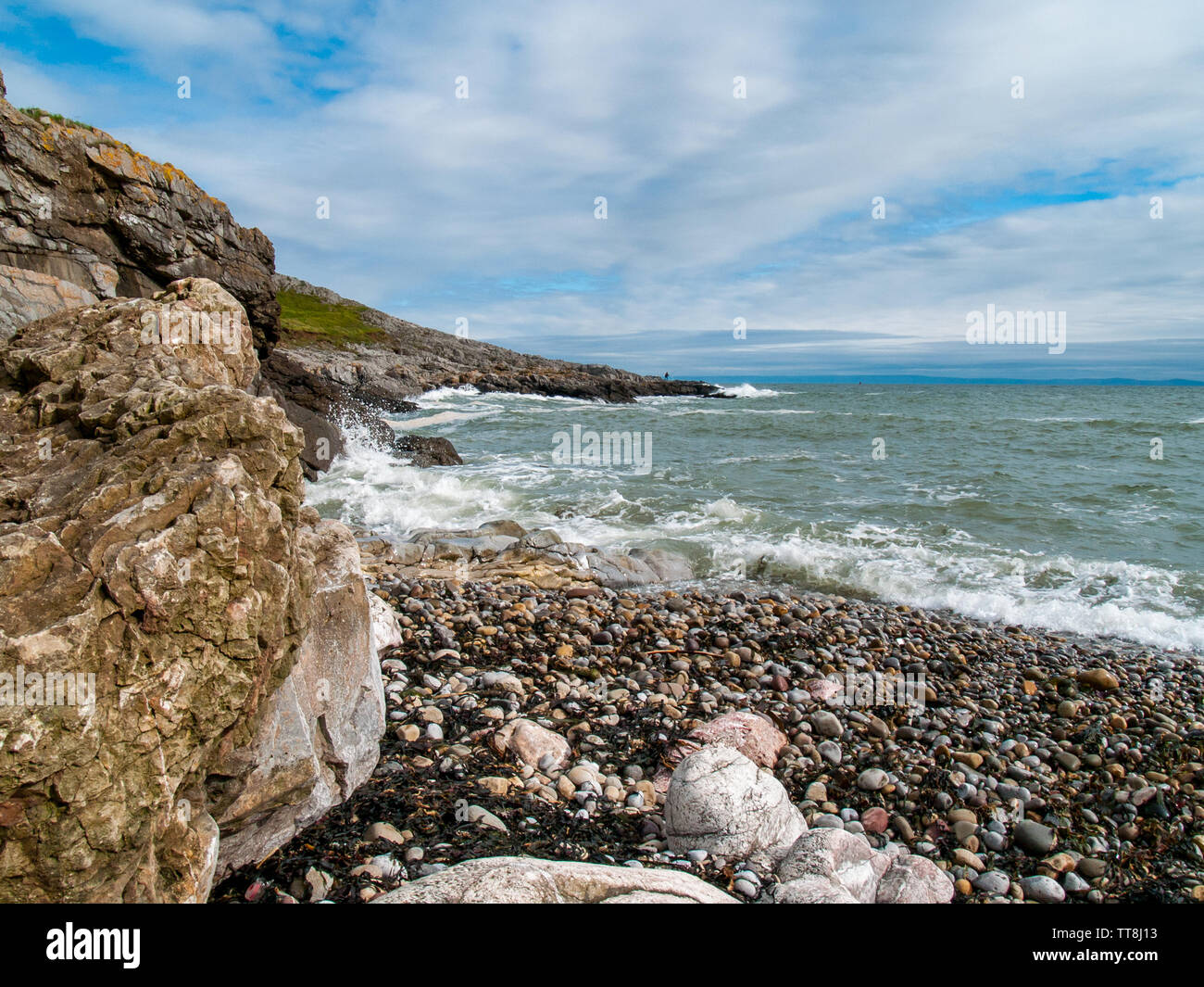 Face à la mer à Limeslade Bay, un pêcheur peut être vu la pêche sur les rochers au loin. Gower, Swansea, Pays de Galles, Royaume-Uni. Banque D'Images