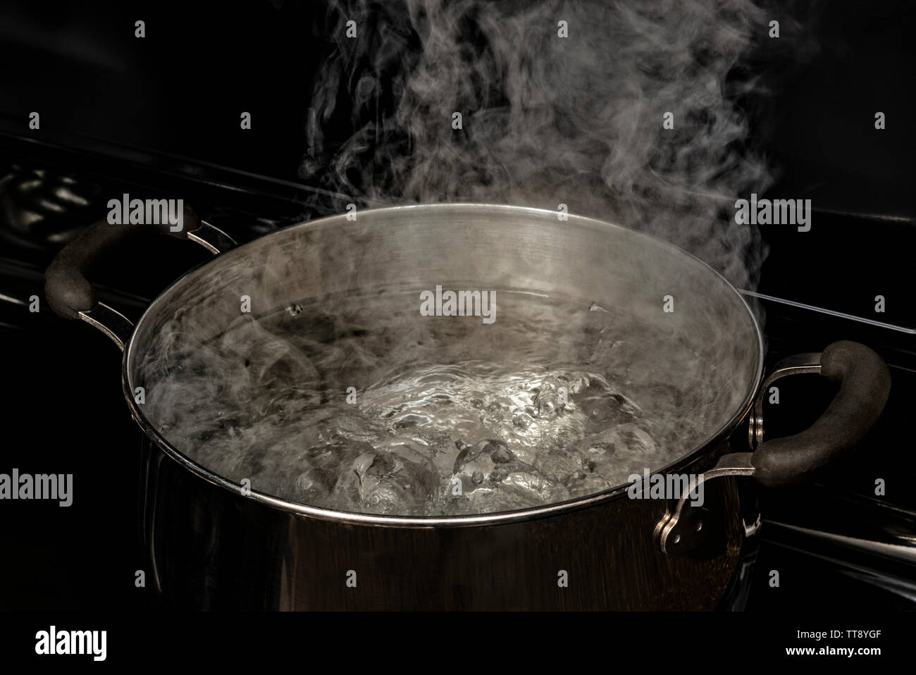 Coup horizontal de l'eau bouillante dans une casserole sur une plaque de cuisson. Banque D'Images