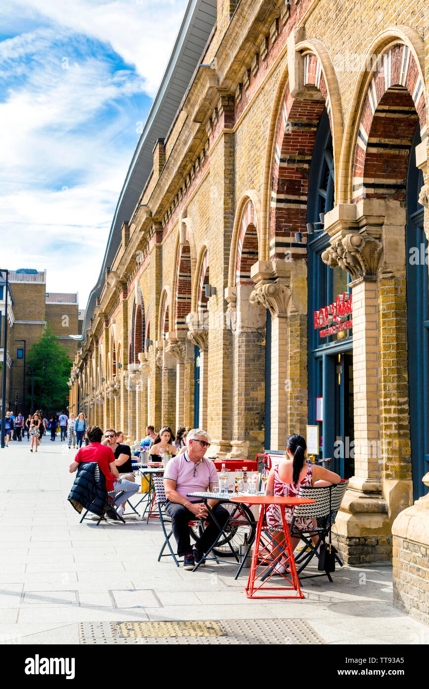 Les gens assis à l'extérieur d'un restaurant à la London Bridge arches sur St Thomas Street, London, UK Banque D'Images