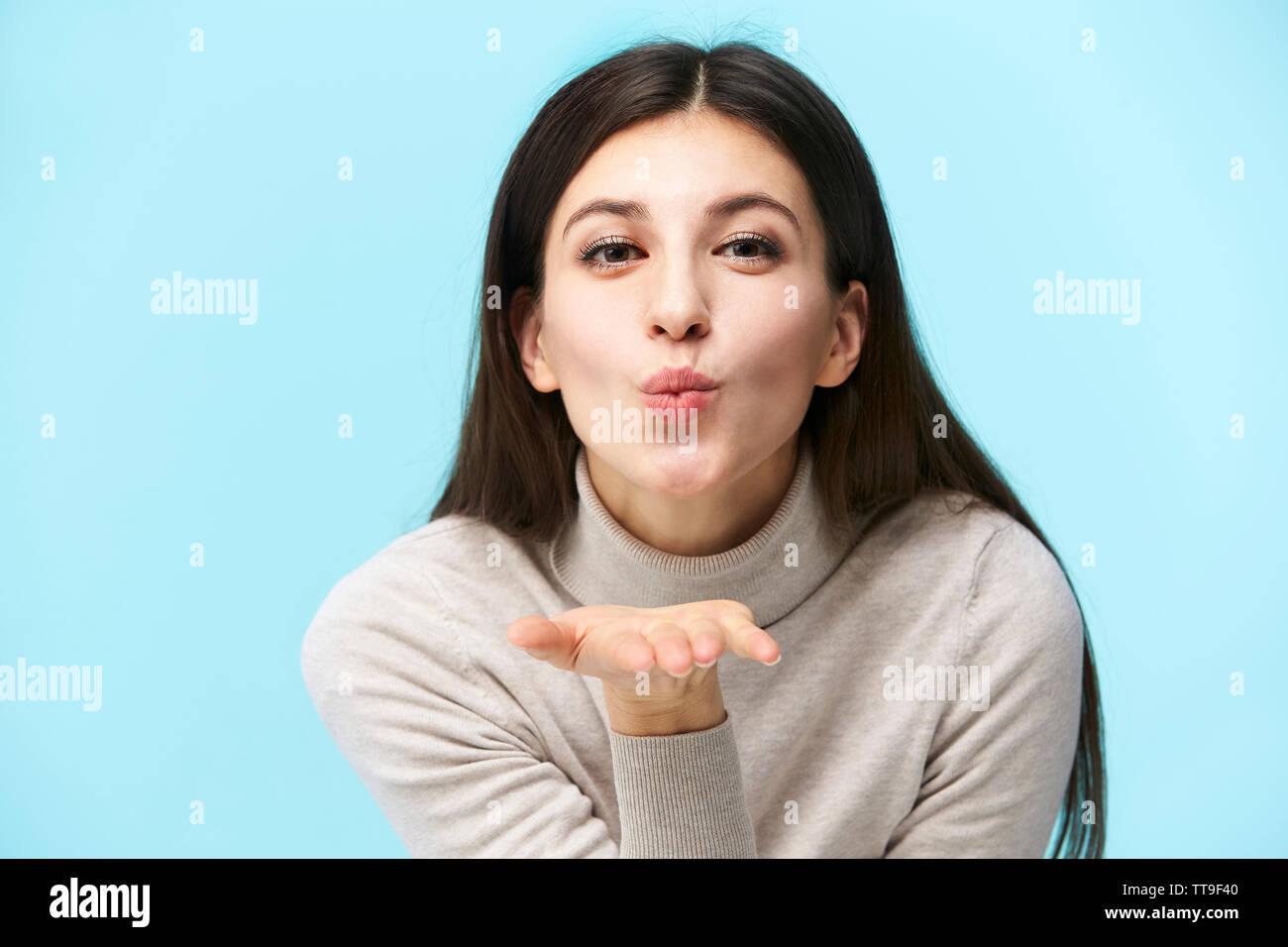 Beau young caucasian woman blowing a kiss, isolé sur fond bleu Banque D'Images