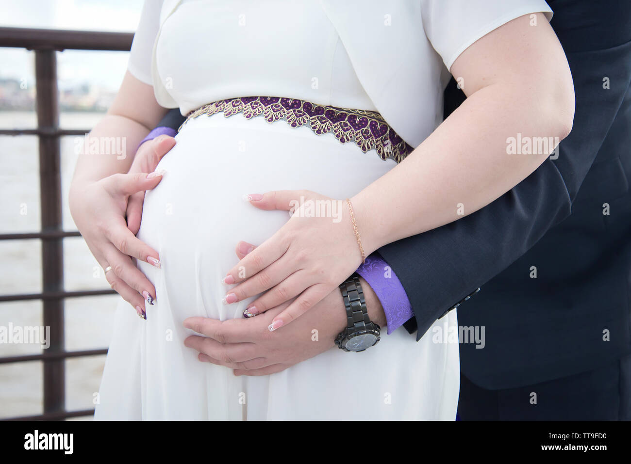 Deux enceintes avec tendresse et l'amour se tenant la main sur son ventre contre une robe blanche Banque D'Images