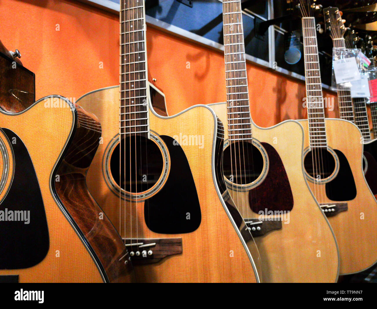 Guitares acoustiques à cordes métalliques suspendus aux murs de music store prêt à effectuer Banque D'Images