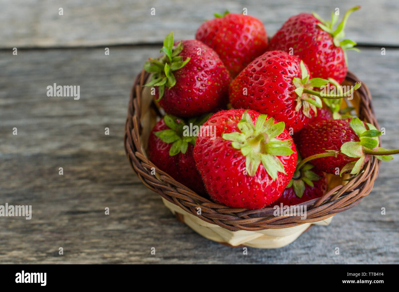 Une fraise mûre dans panier en osier sur la vieille table en bois Banque D'Images