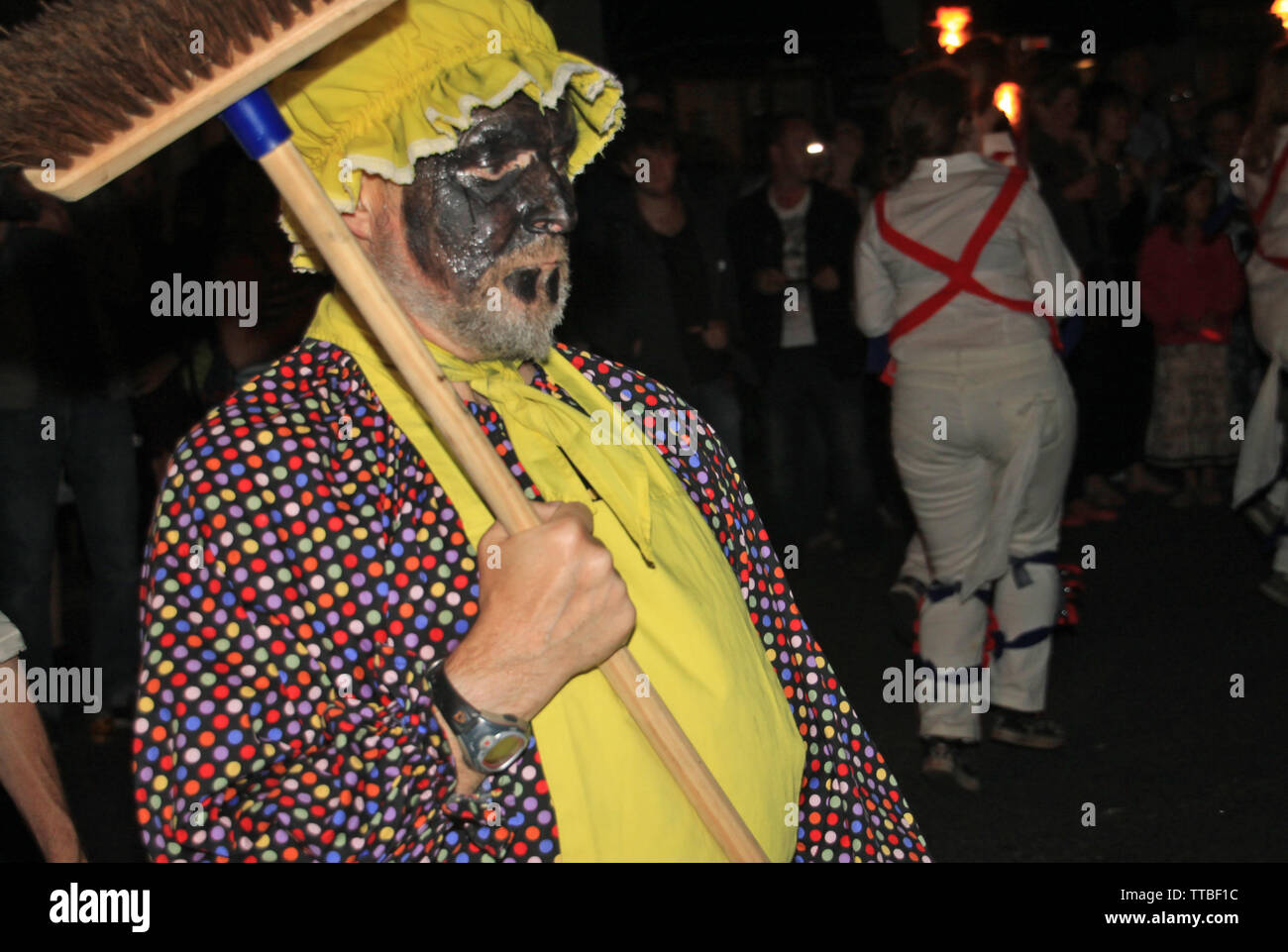 La ville de Sidmouth, Devon, Angleterre - 10 août 2012 : un homme avec un balai et d'un tablier jaune mène un troup de danseurs Morris anglais traditionnel prend part à t Banque D'Images