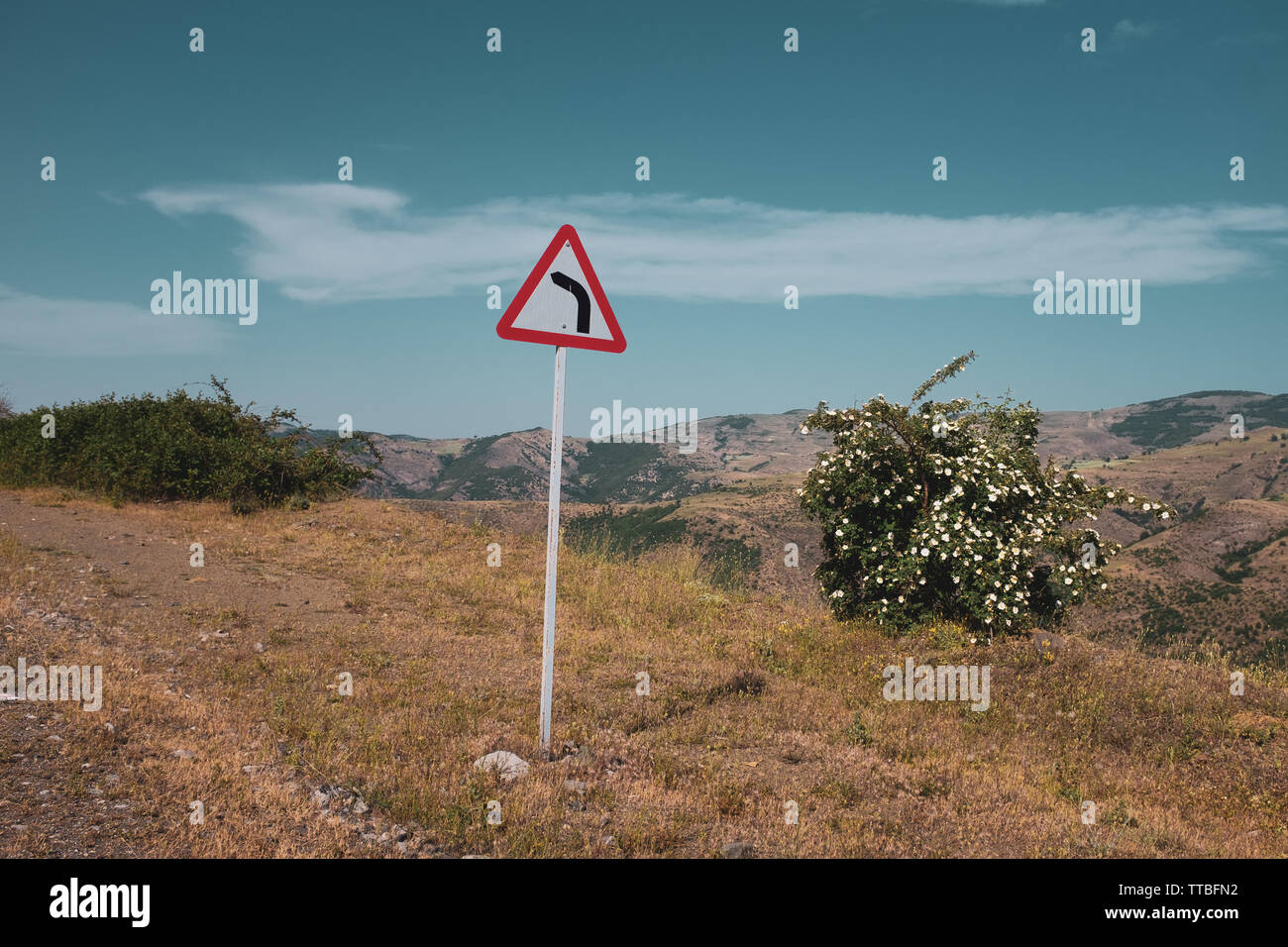 Signalisation routière dangereux, tournez à gauche, extérieur, montagne, ciel bleu, vide. Banque D'Images