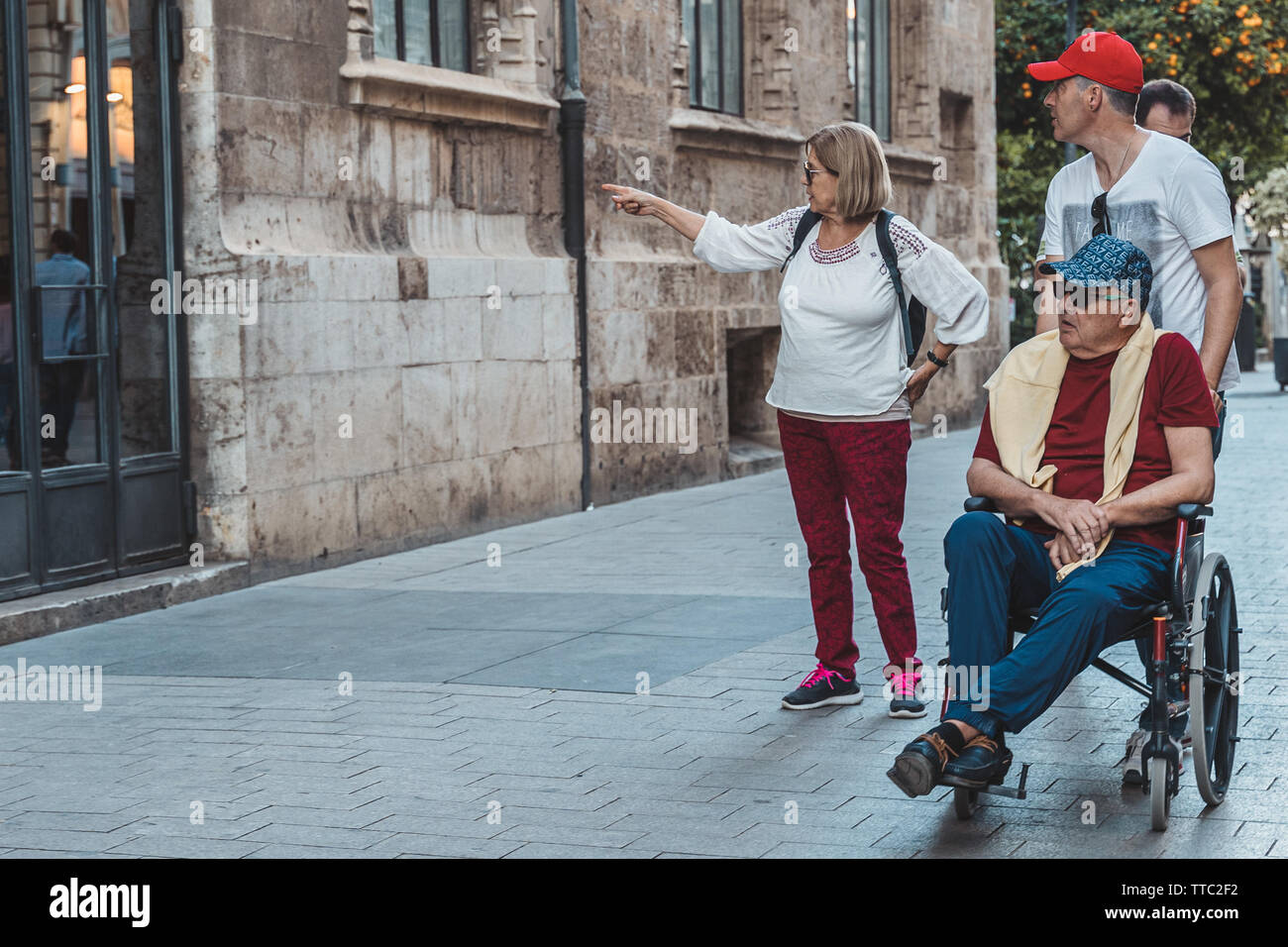 Valence, Espagne - juin 1, 2019 : fils prendre soin de son vieux père sur le fauteuil roulant. Personnes âgées de la famille. Banque D'Images