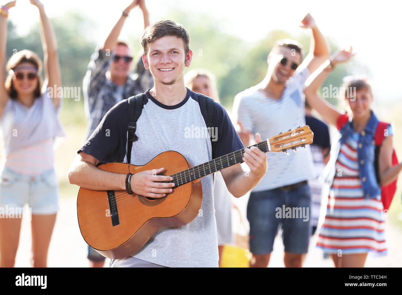 Beau jeune homme joue de la guitare contre l'extérieur, les amis de la danse Banque D'Images