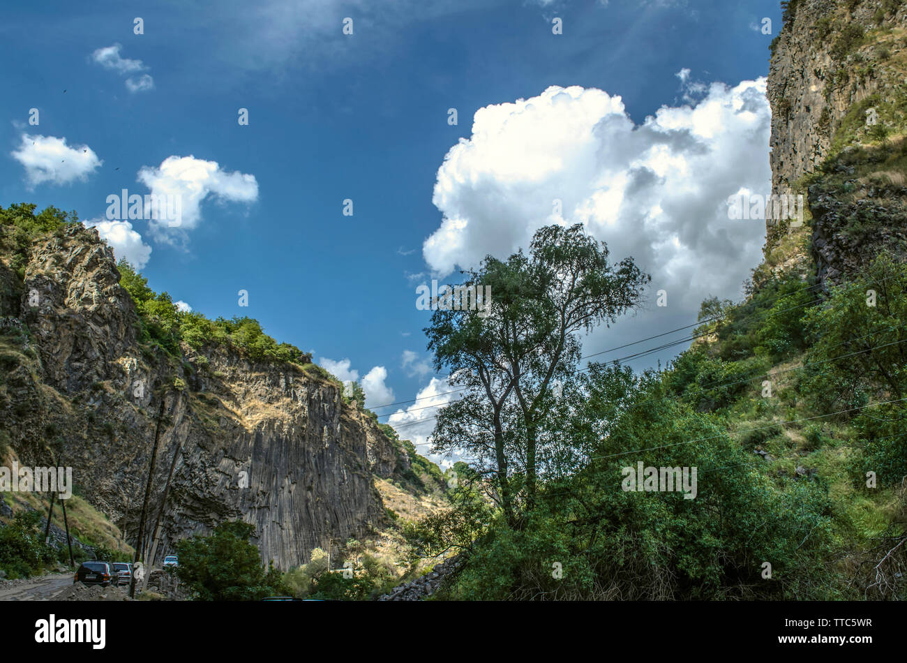 Route de montagne vers Garni, à proximité des roches de basalte permanent verticalement et les collines sur le fond bleu du ciel couvert de nuages Banque D'Images