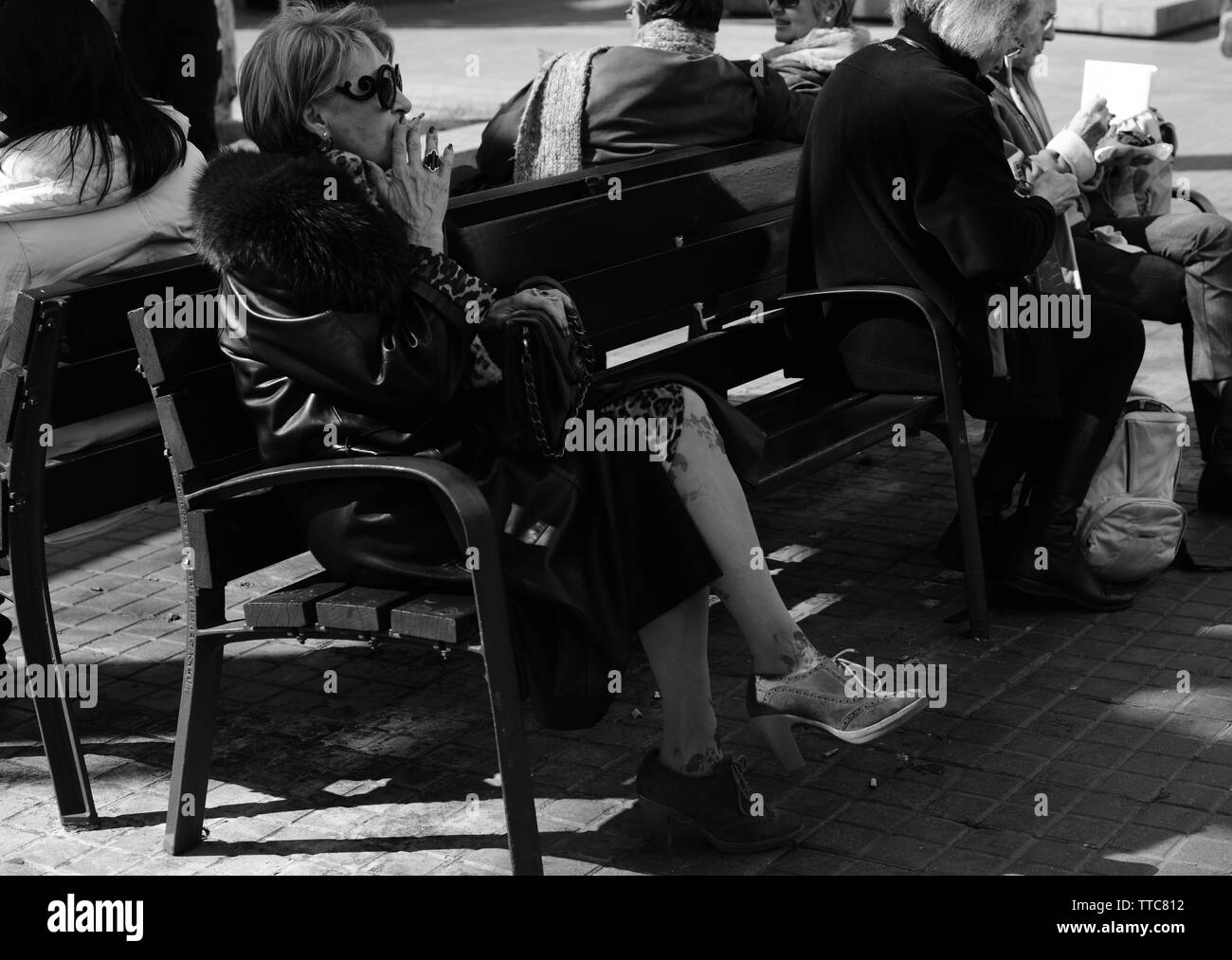 Vieille femme était assise sur un banc, fumant une cigarette Banque D'Images