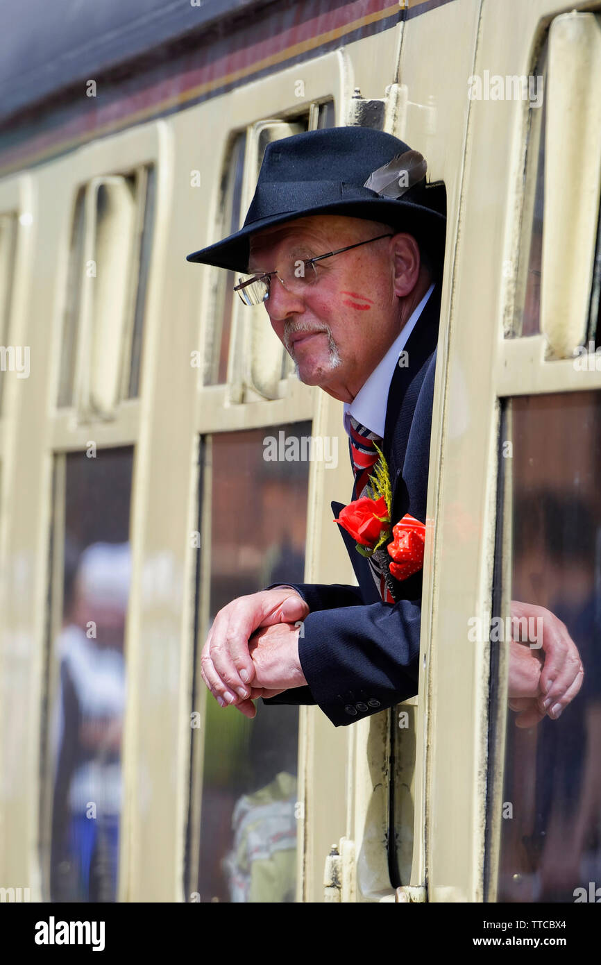 L'homme vêtu d'un costume se penchant hors de la fenêtre d'un wagon de chemin de fer Banque D'Images