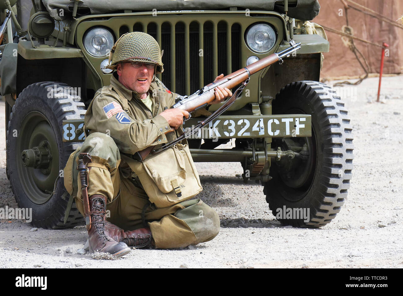 Reenactor habillé comme un soldat de l'Armée U.S 82nd Airborne "tous Américains" assis en face d'une Jeep Banque D'Images