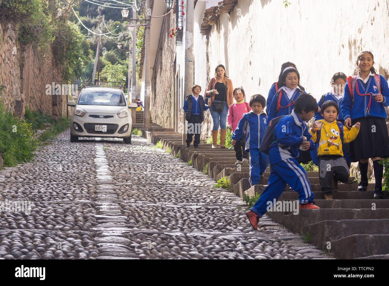 Scène de rue Cusco - enfants écoliers marchant dans l'étroite rue en pente à Cusco, Pérou, Amérique du Sud. Banque D'Images