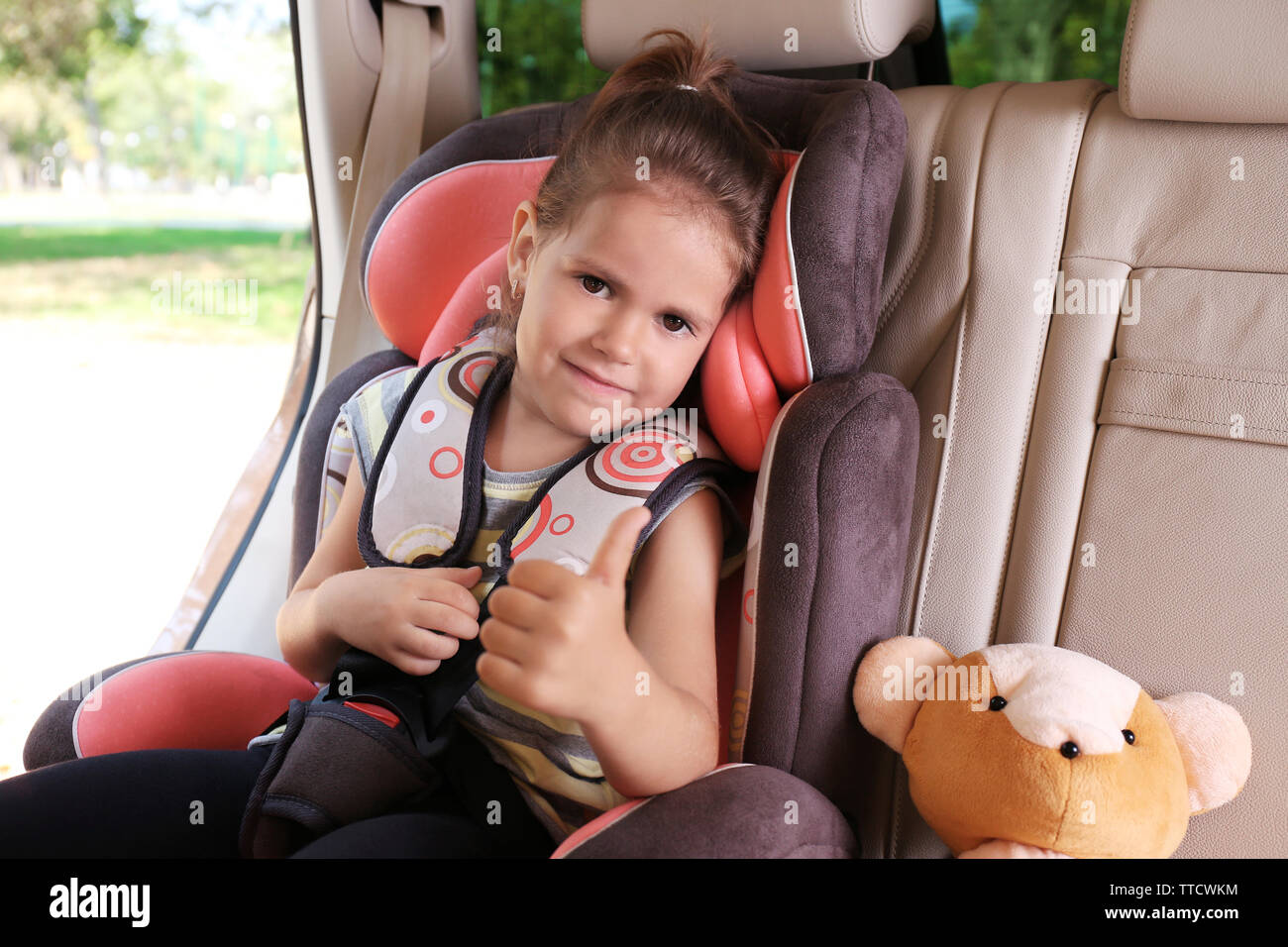 Adorable petite fille dans la voiture avec ours Banque D'Images