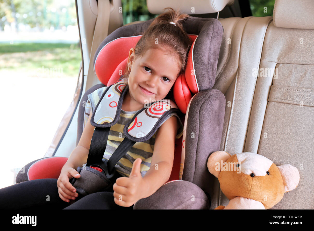 Adorable petite fille dans la voiture avec ours Banque D'Images