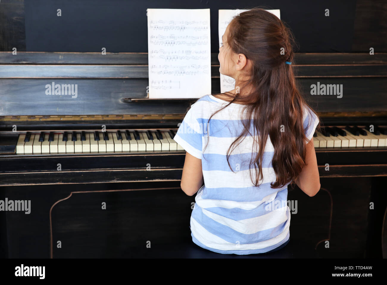 Cute little girl musicien joue du piano, vue arrière Banque D'Images