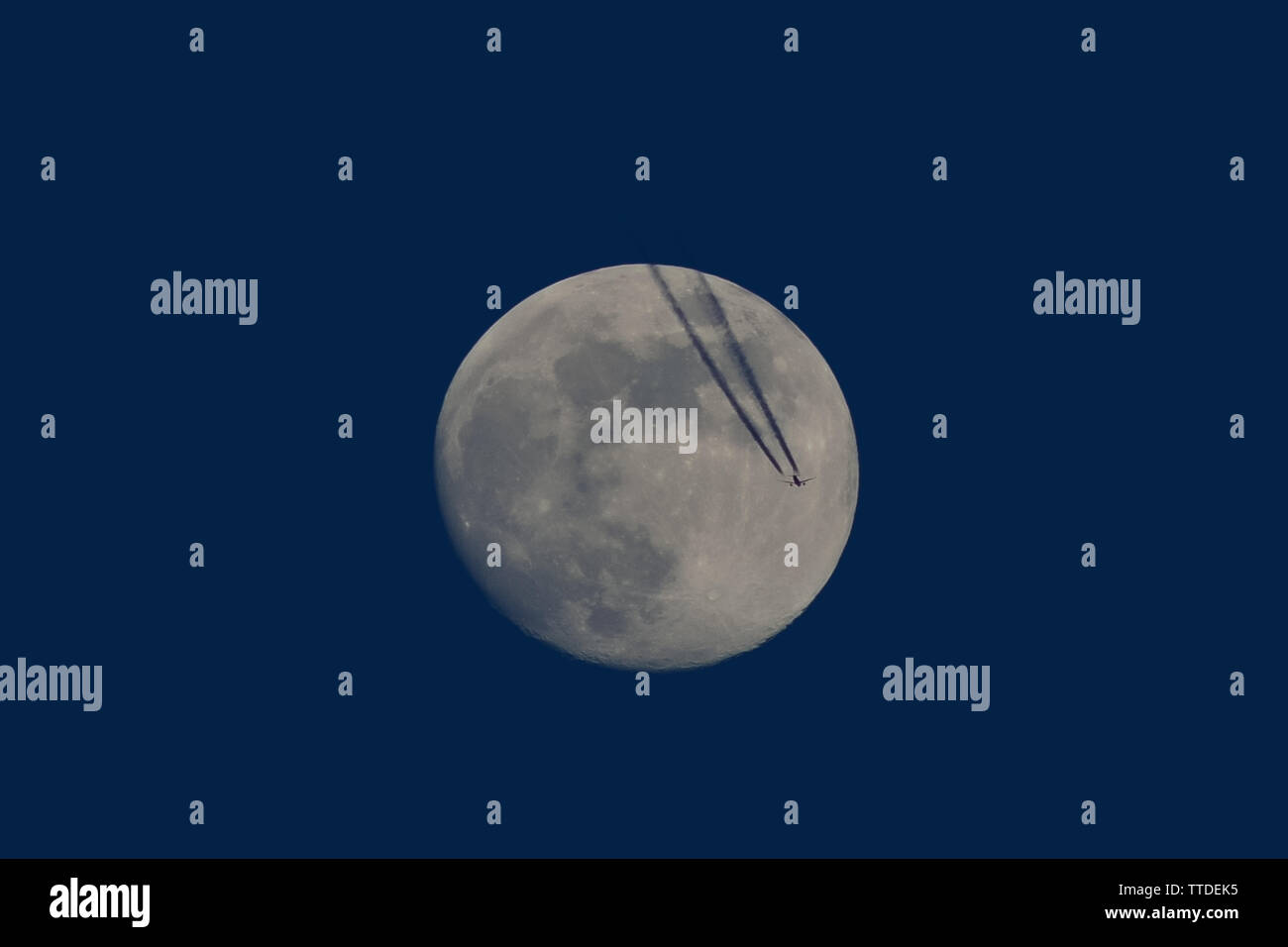 Silhouette d'avion avec vol de pleine lune contrail Banque D'Images