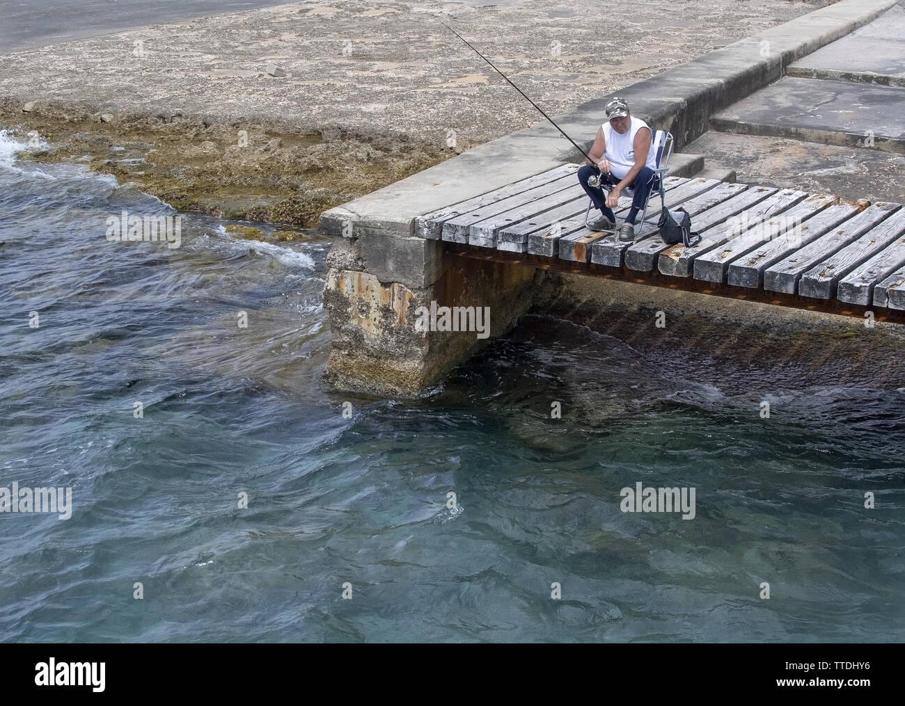 SANTA PONSA, Mallorca, Espagne - 29 MAI 2019 : pêcheur détendue assis sur un pont en bois par l'eau le 29 mai 2019 à Santa Ponsa, Mallorca, Espagne Banque D'Images