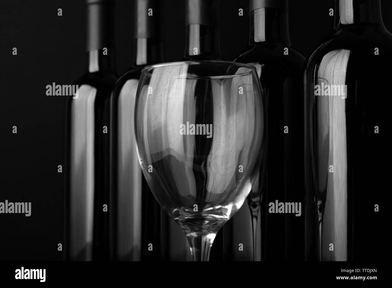 Le verre et les bouteilles de vin dans une rangée sur fond noir, Close up Banque D'Images