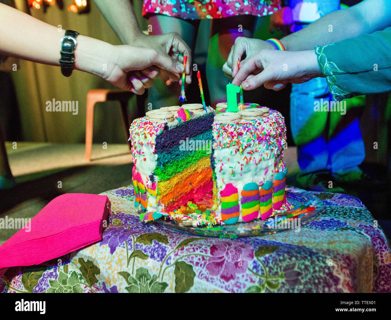 Un gâteau arc-en-ciel est coupé par un groupe diversifié de personnes LGBT queer lors d'une célébration partie à Kuala Lumpur, Malaisie. Banque D'Images