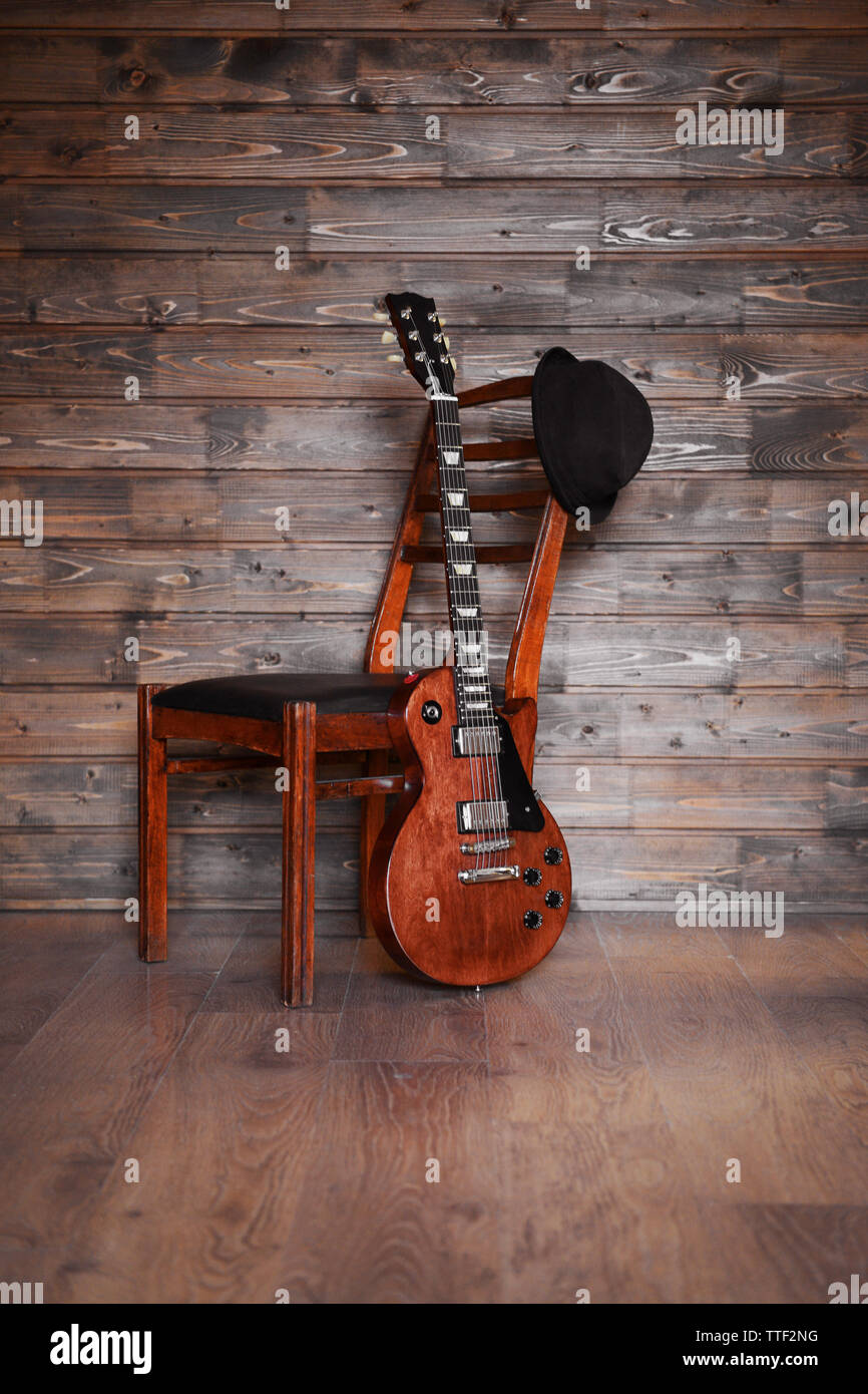 Brown guitare électrique avec une chaise et un chapeau noir sur fond de  bois, Close up Photo Stock - Alamy