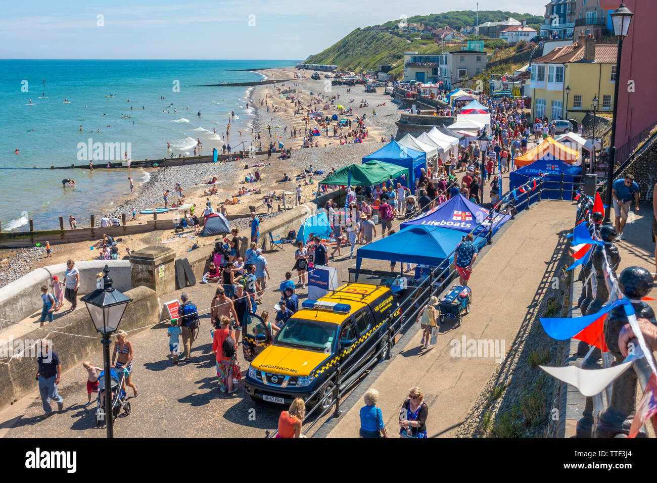 Plage, mer, promenade et de nombreux visiteurs de Cromer, sur une chaude journée d'été. Sauvetage et Garde-côtes sont positionnés à proximité. Cromer, Norfolk, Angleterre, Royaume-Uni. Banque D'Images