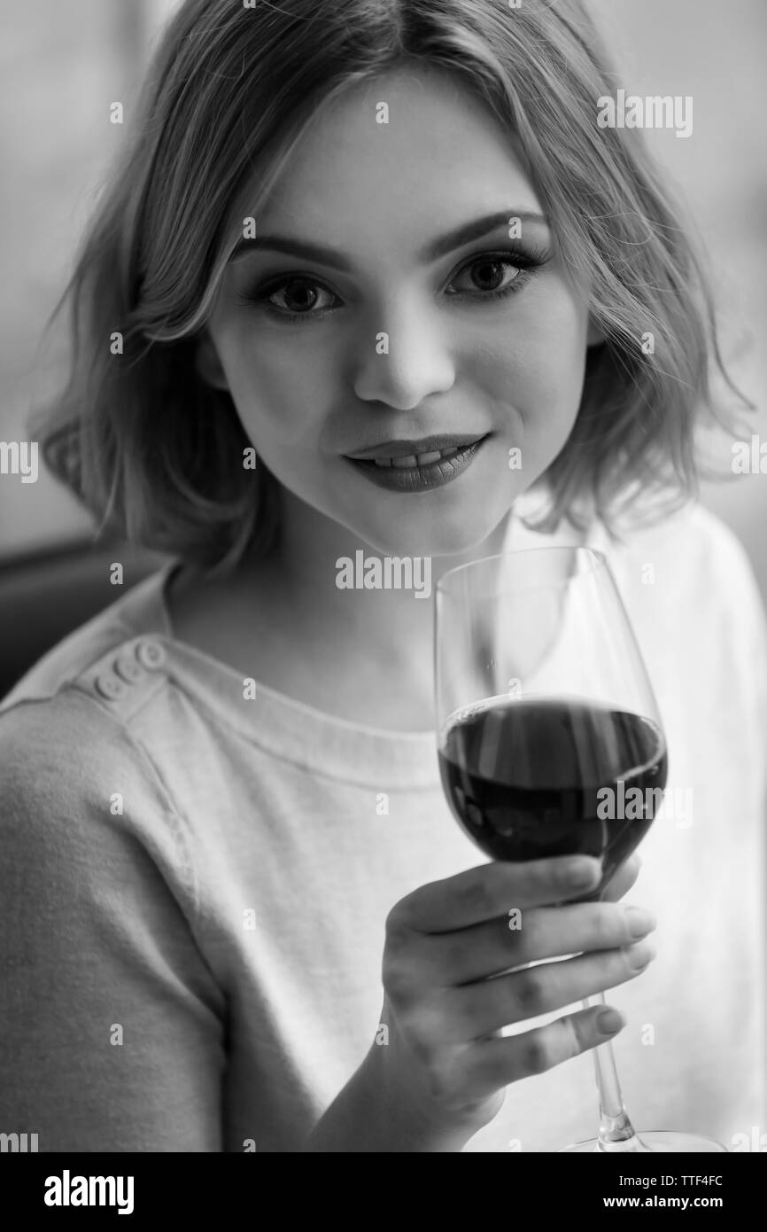 Jeune femme avec verre de vin rouge dans des tons de gris Banque D'Images