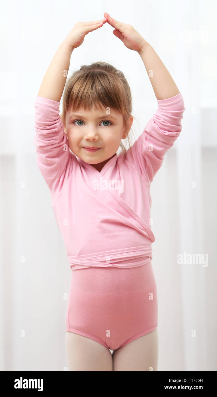 Petite fille mignonne en rose de danseur faisant de nouveaux mouvements de ballet au studio de danse Banque D'Images