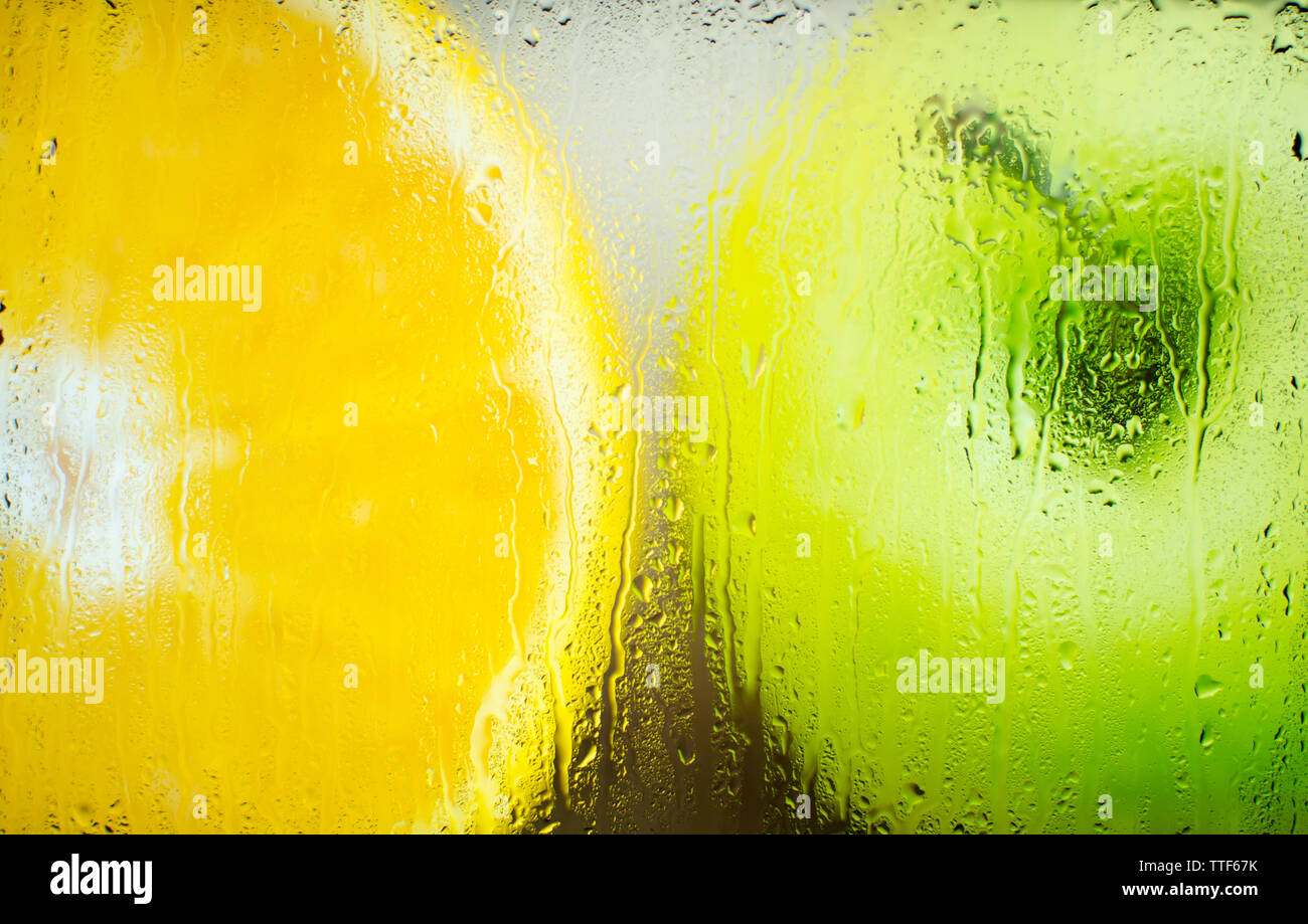 Apple et orange dans un verre dépoli après la pluie Banque D'Images