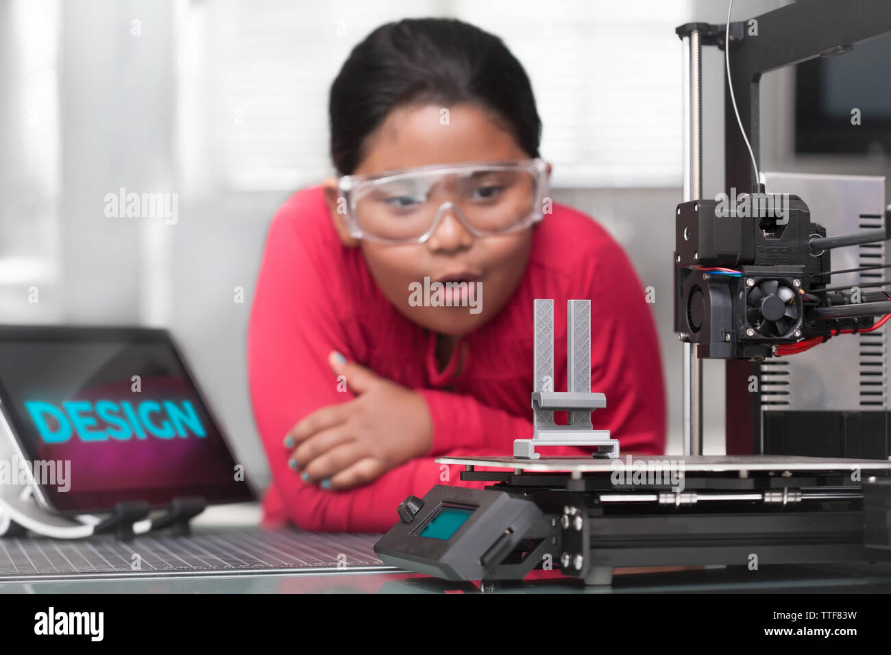 Une jeune fille hispanique est étonné qu'elle regarde son 3d printed projet dans une classe d'été de la tige. Banque D'Images