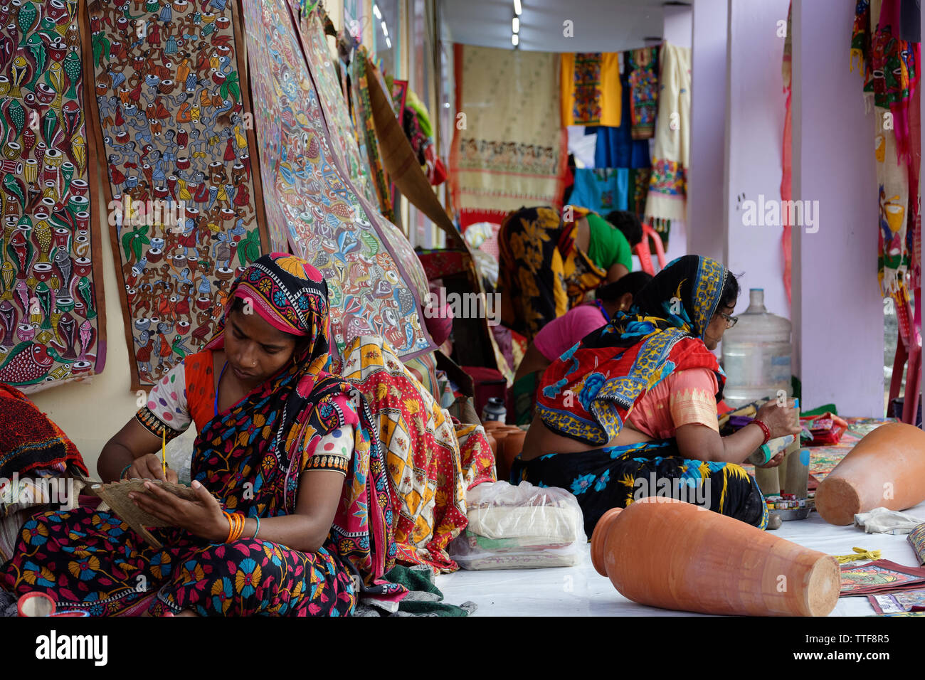 Les femmes rurales indiennes peinture artiste en face d'une tapisserie murale Banque D'Images
