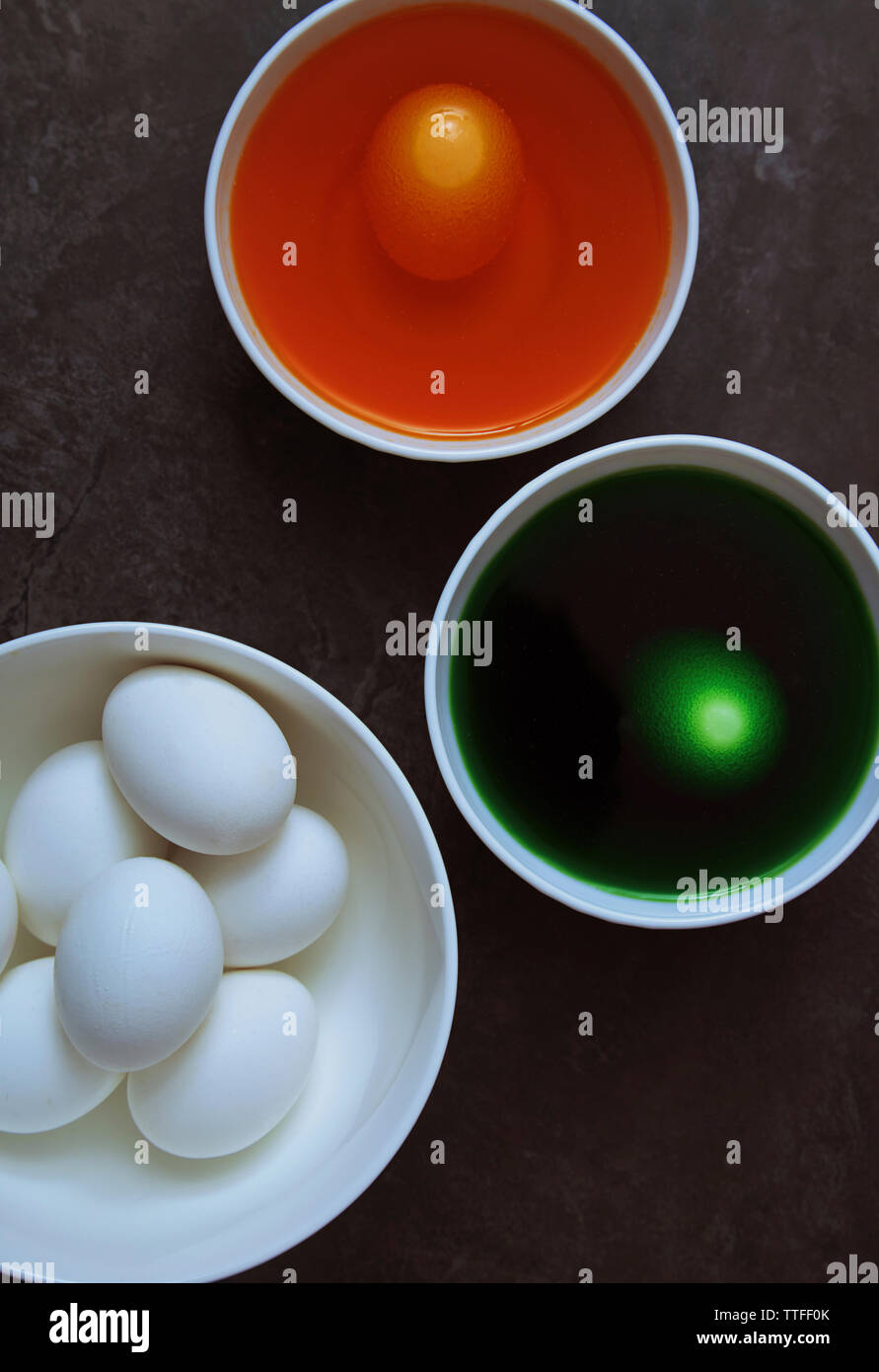 Vue aérienne des oeufs et colorant alimentaire dans des bols pour la décoration de pâques sur la table Banque D'Images