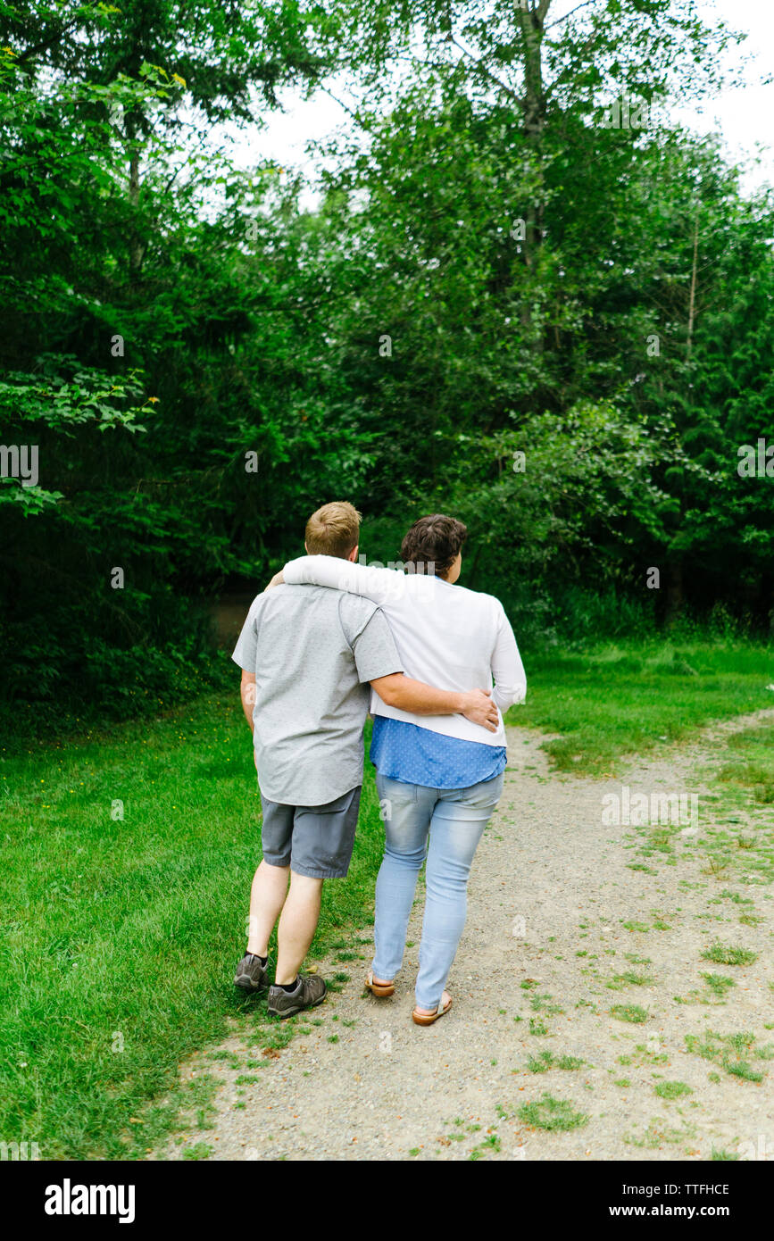 Vue arrière d'un couple en train de marcher ensemble sur un sentier dans un parc de la ville Banque D'Images