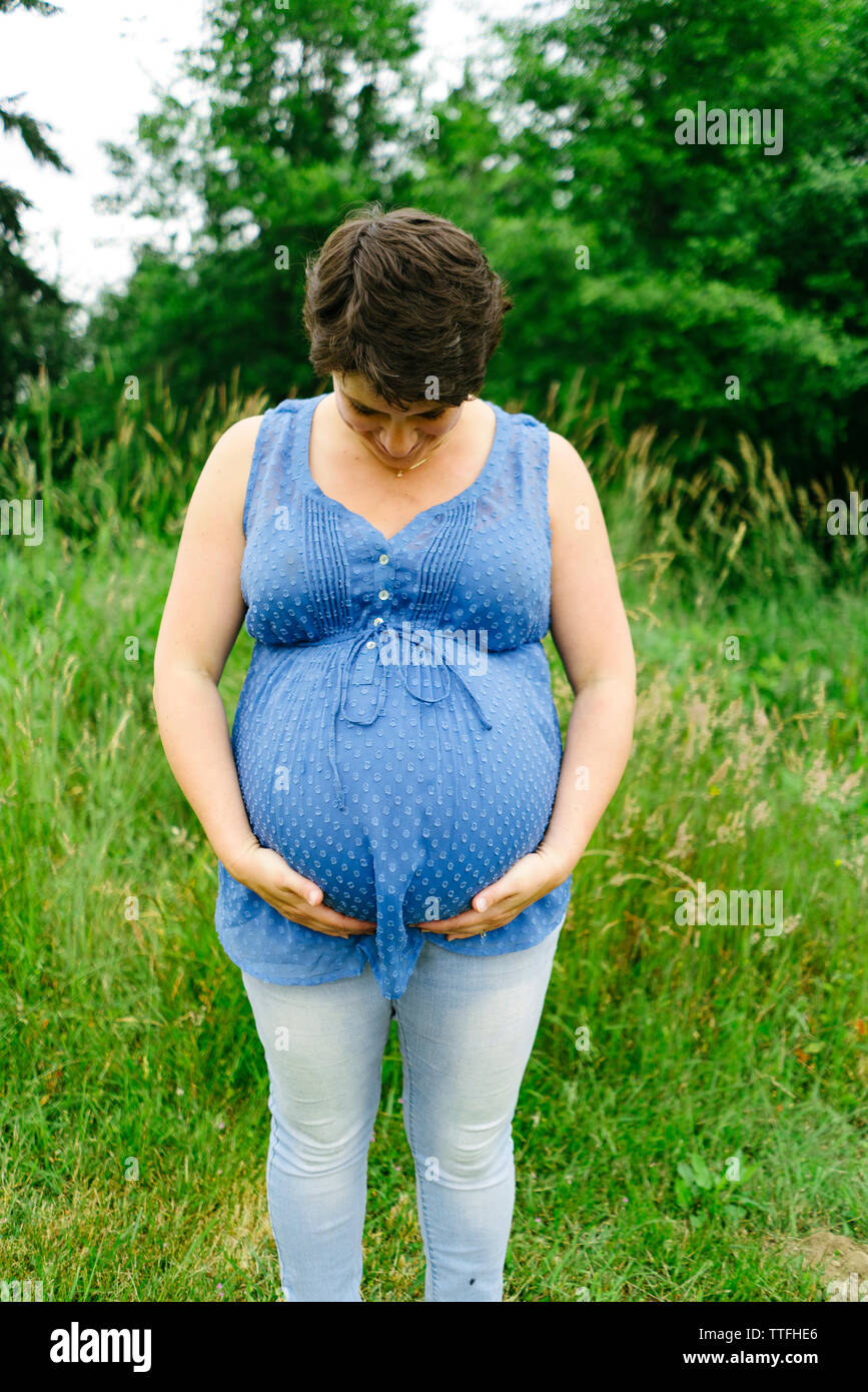 Tout droit sur portrait of a pregnant woman standing in tall grass Banque D'Images