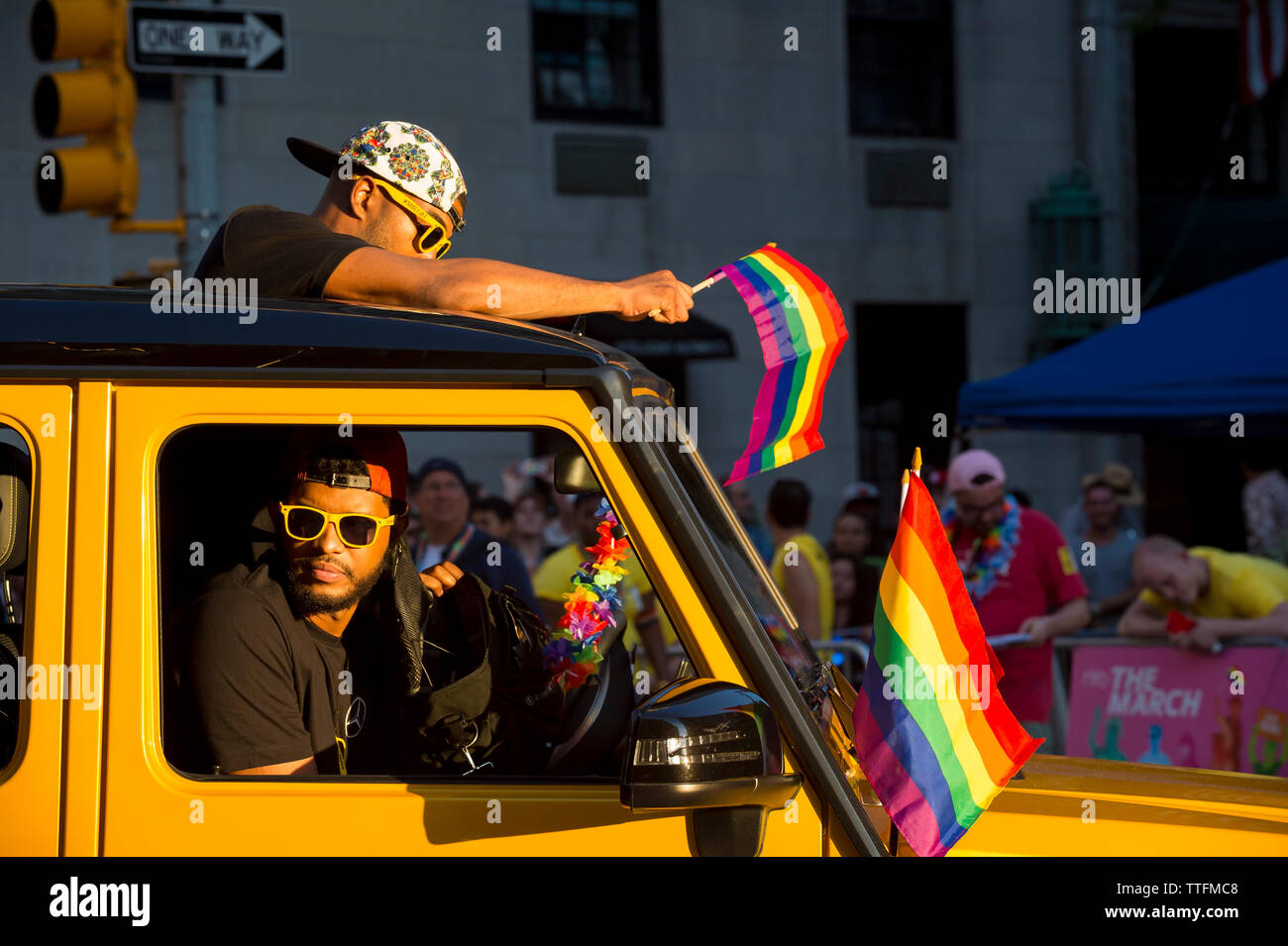 NEW YORK - 25 juin 2017 : les jeunes hommes à travers la Gay Pride Parade annuelle en agitant des drapeaux arc-en-ciel en passant par Greenwich Village. Banque D'Images