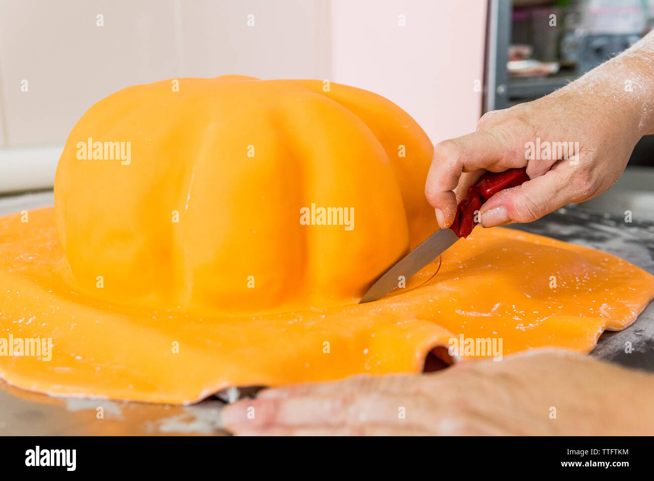 Chef pâtissier la coupe de pâte à sucre un gâteau avec une forme de citrouille Banque D'Images