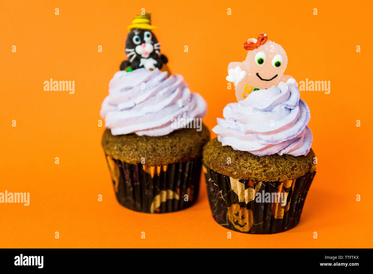 Deux drôle halloween cupcakes avec un chat de Cheshire et un fantôme sur la crème Banque D'Images