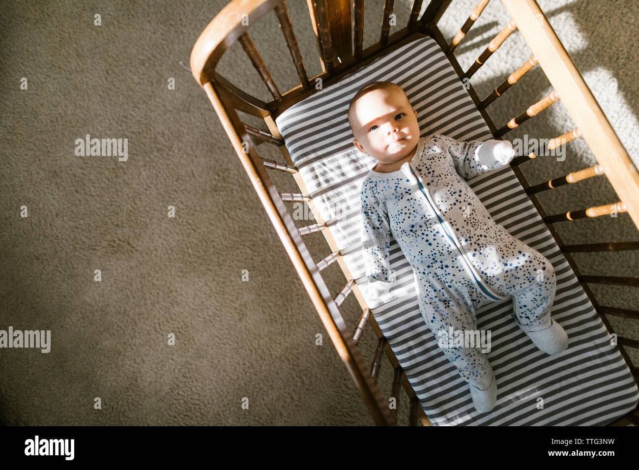 La lumière du soleil et ombres projetées sur un bébé dans un berceau en bois de pose Banque D'Images