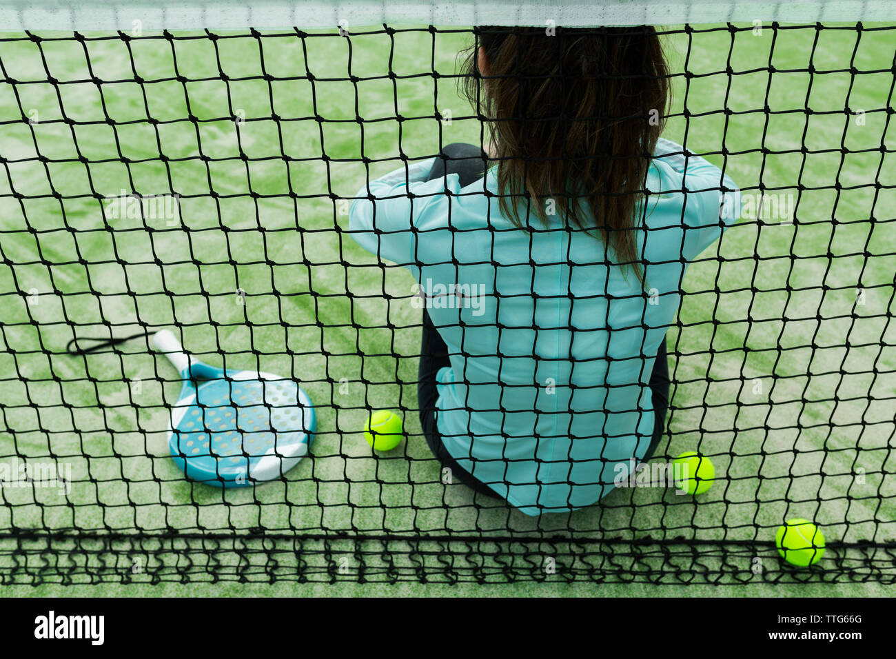 Vue arrière de femme assise sur un court de tennis par net Banque D'Images