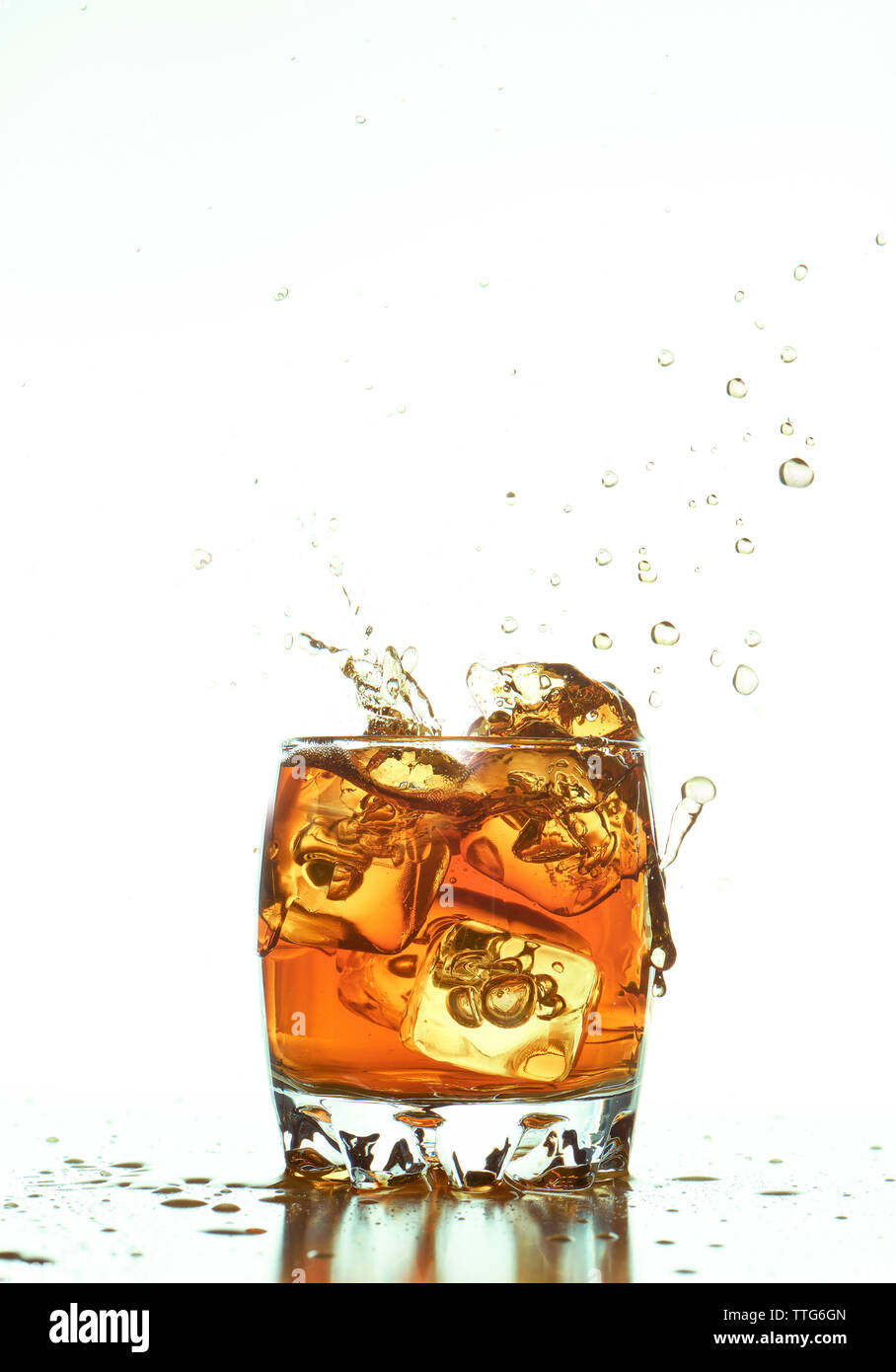 Ice cubes splashing in whiskey sur fond blanc Banque D'Images