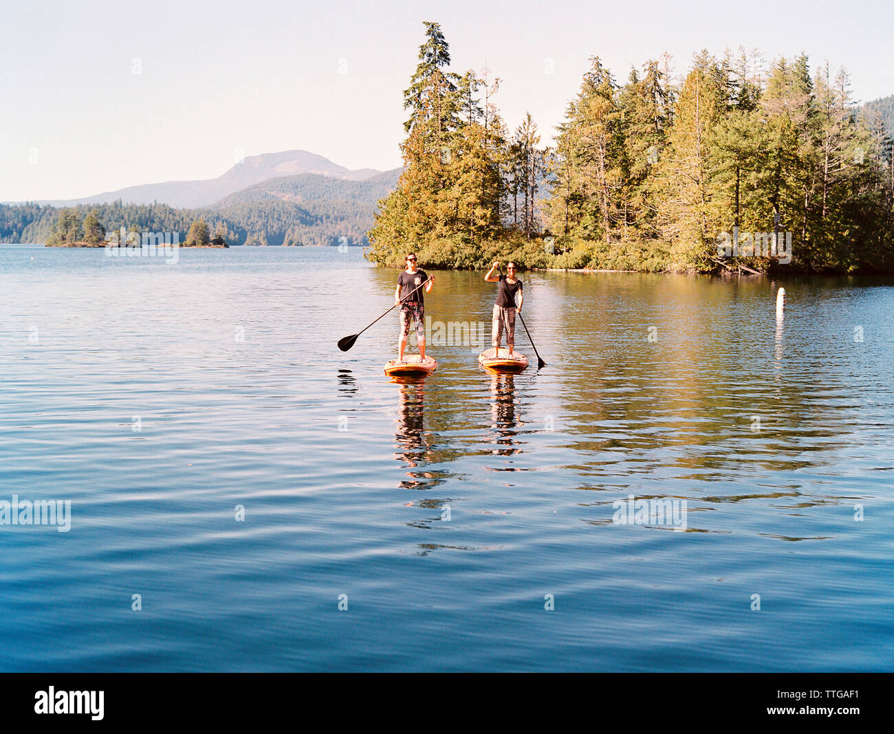 2 jeunes femmes stand-up paddle dans le lac Banque D'Images