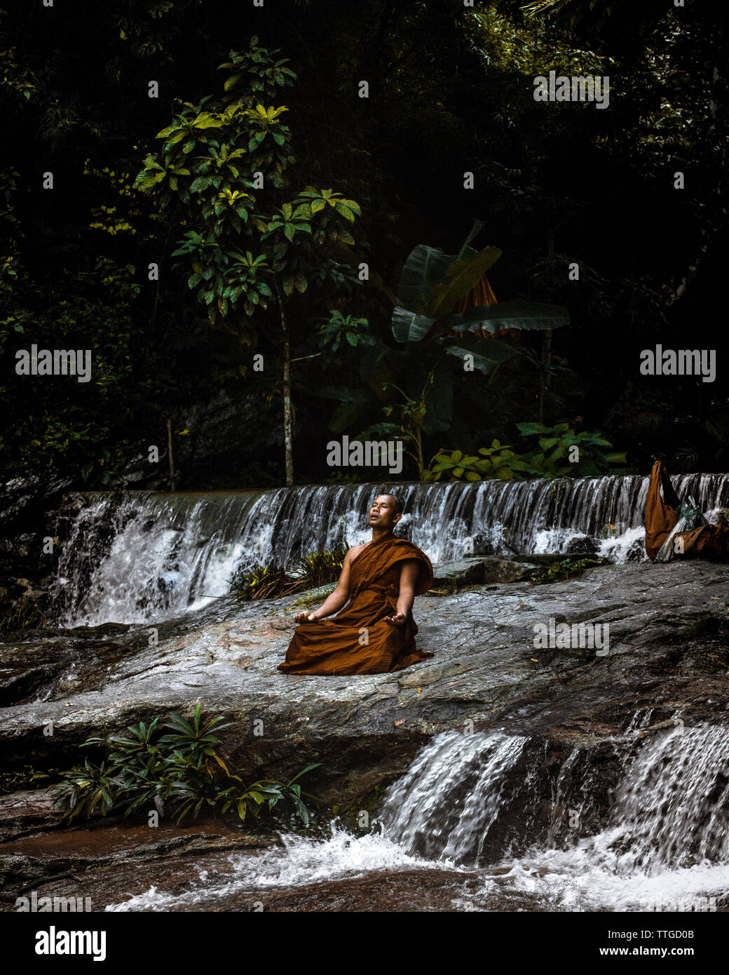 Monk méditant par cascade Banque D'Images