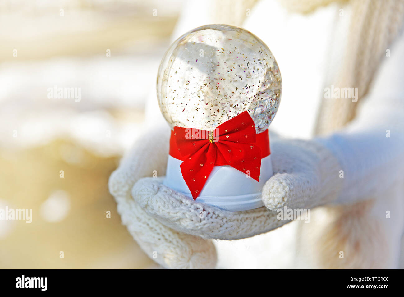 Fille de mitaines tricotées holding glass ball arc rouge avec piscine Banque D'Images