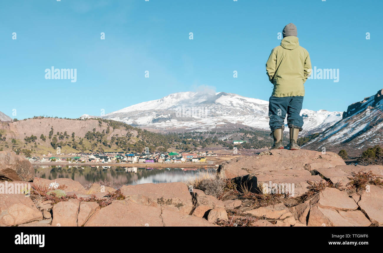 Un homme se tient sur un rocher ressemble à Caviahue, et Volcan Copahue. Banque D'Images