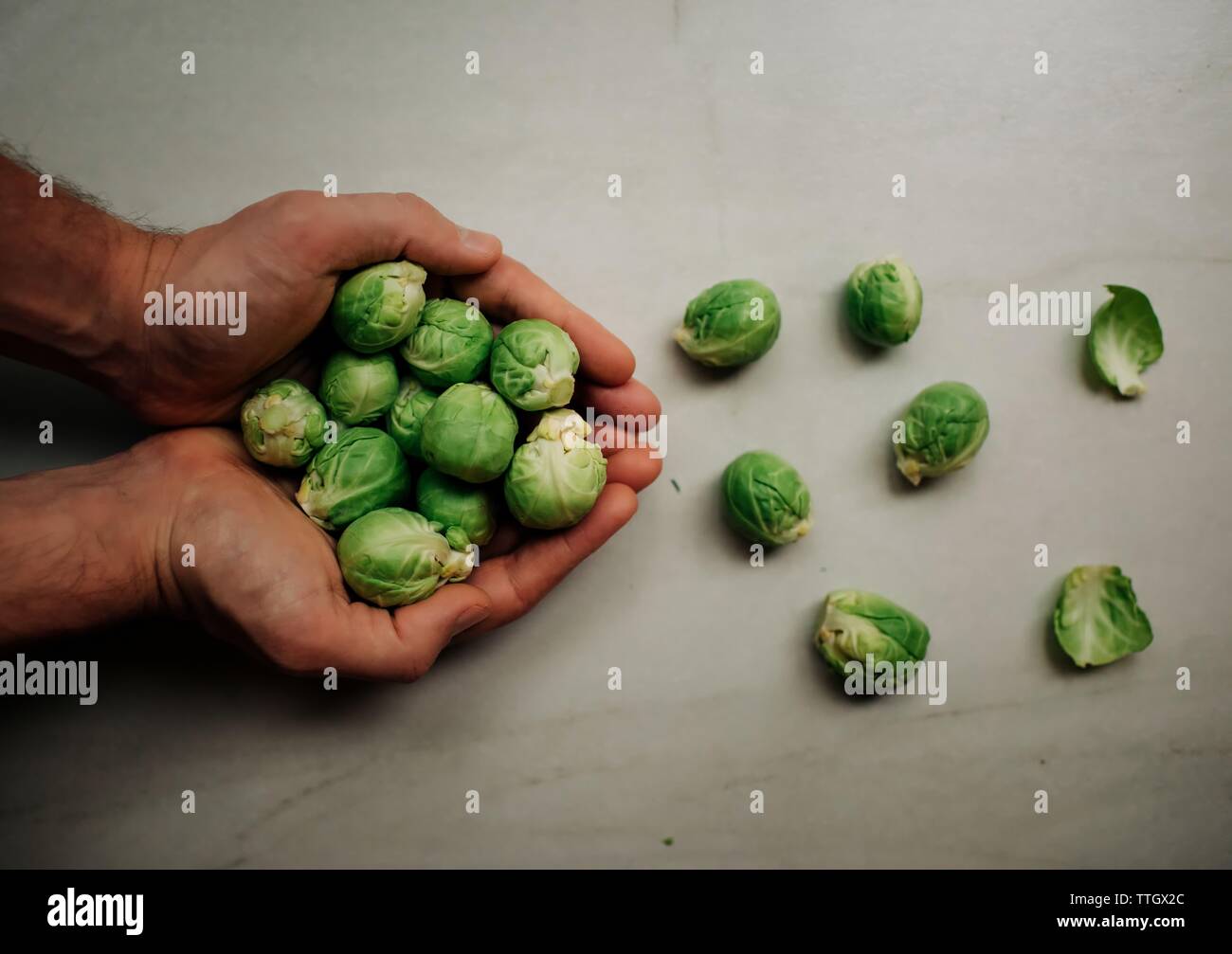 Les choux de Bruxelles dans les mains des chefs sur planche à découper Banque D'Images