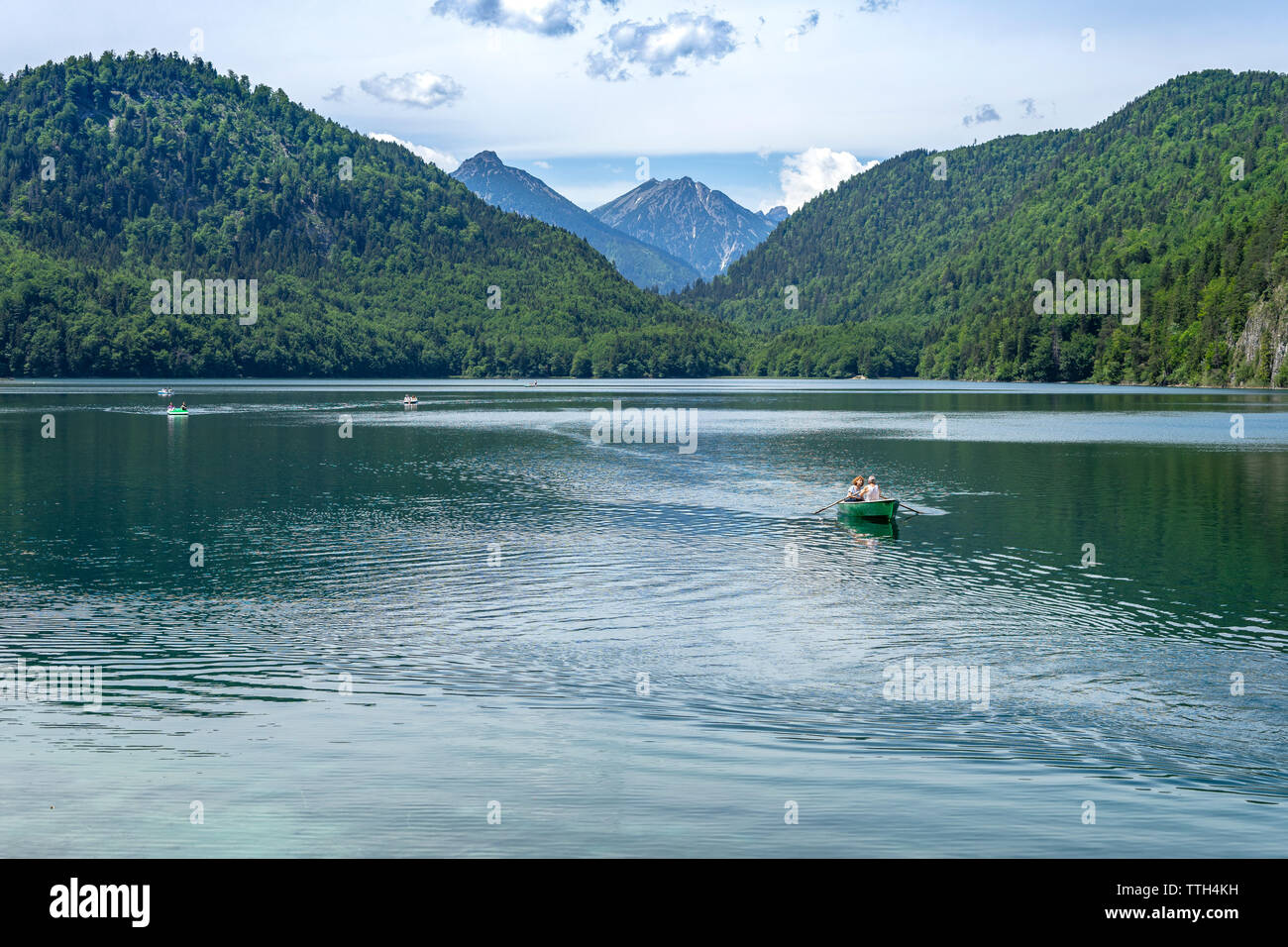 Couple crossing mountain lake Alpsee sur une barque Banque D'Images