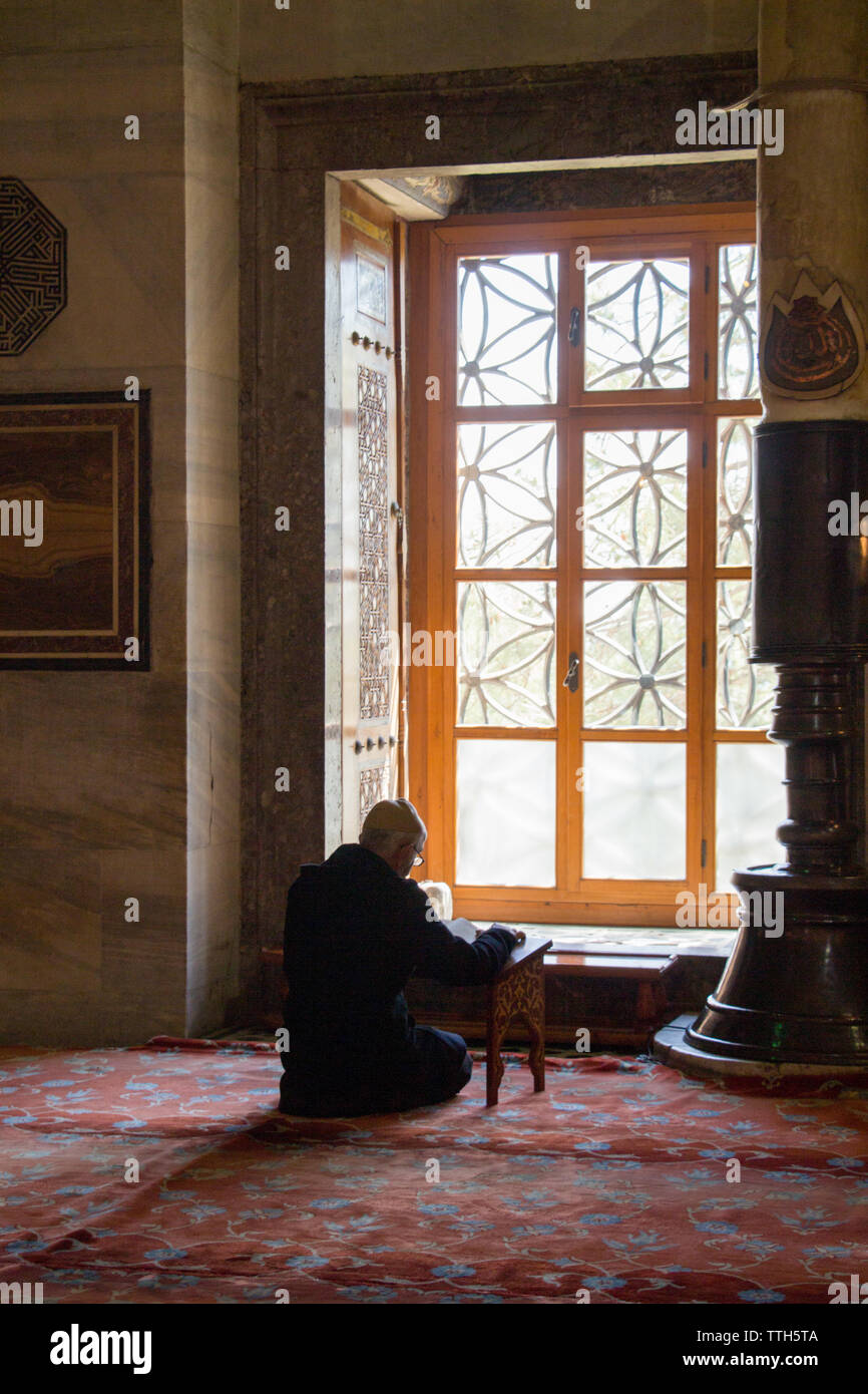 Vieil homme lecture Coran dans une mosquée sur l'affichage Banque D'Images